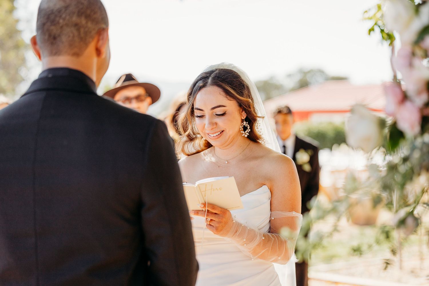 A couple shares a romantic moment during their outdoor wedding ceremony in warm golden sunlight.