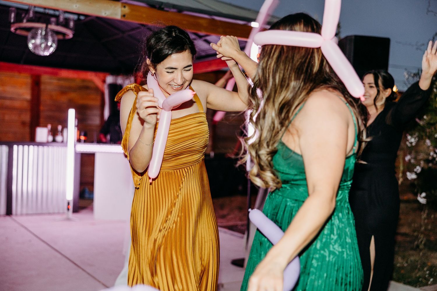 Wedding reception dance floor with guests in colorful dresses celebrating.