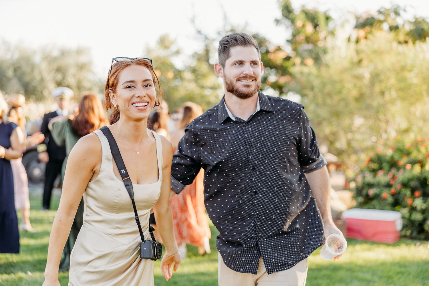 A couple walks and laughs together in a sunny outdoor park setting during golden hour.