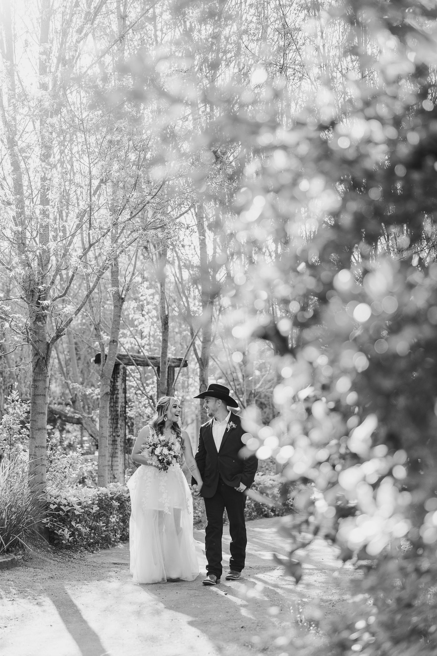 Dreamy black and white wedding photos of couple walking through wooded area.