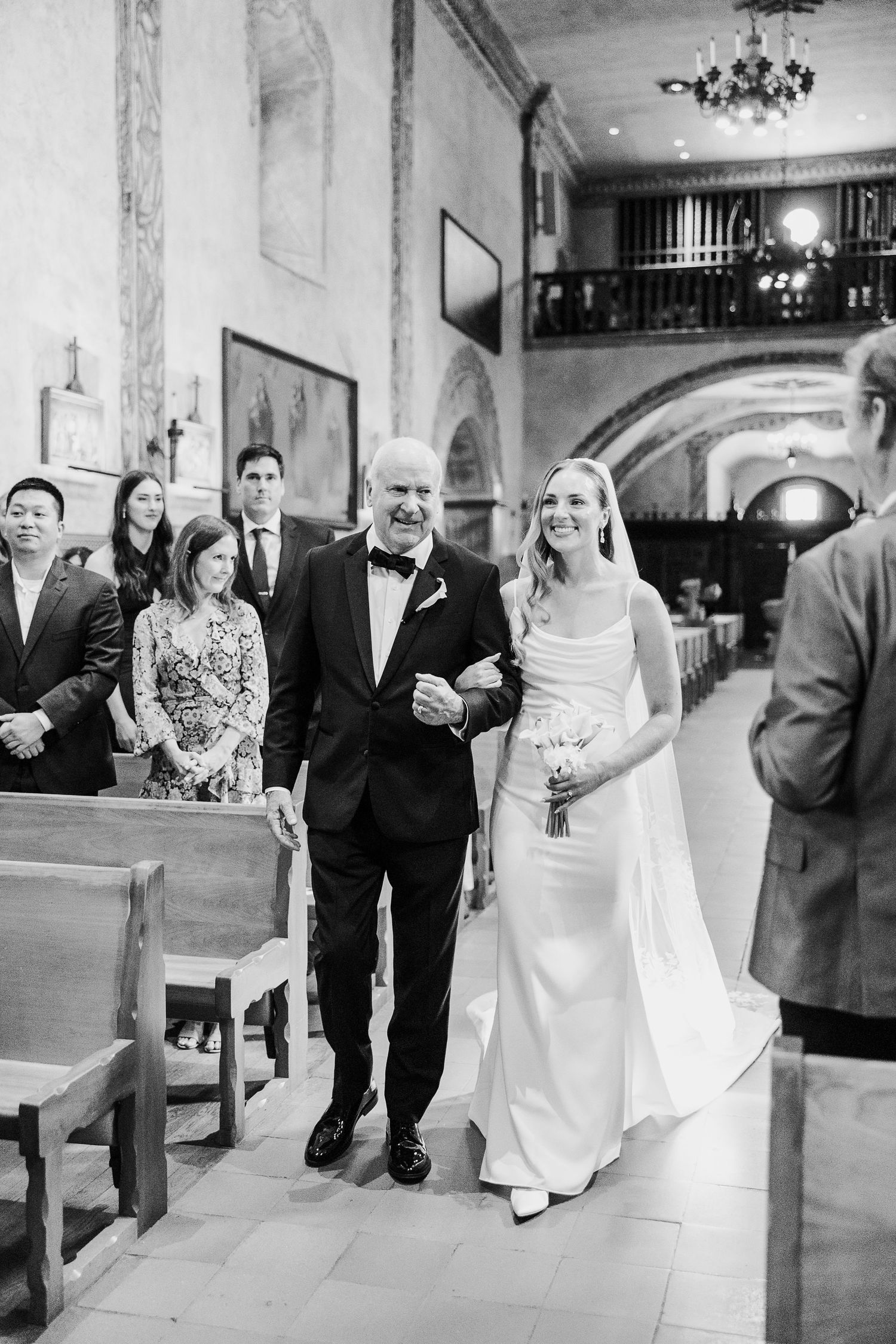 Wedding party walks through elegant indoor venue in black and white photo sequence.