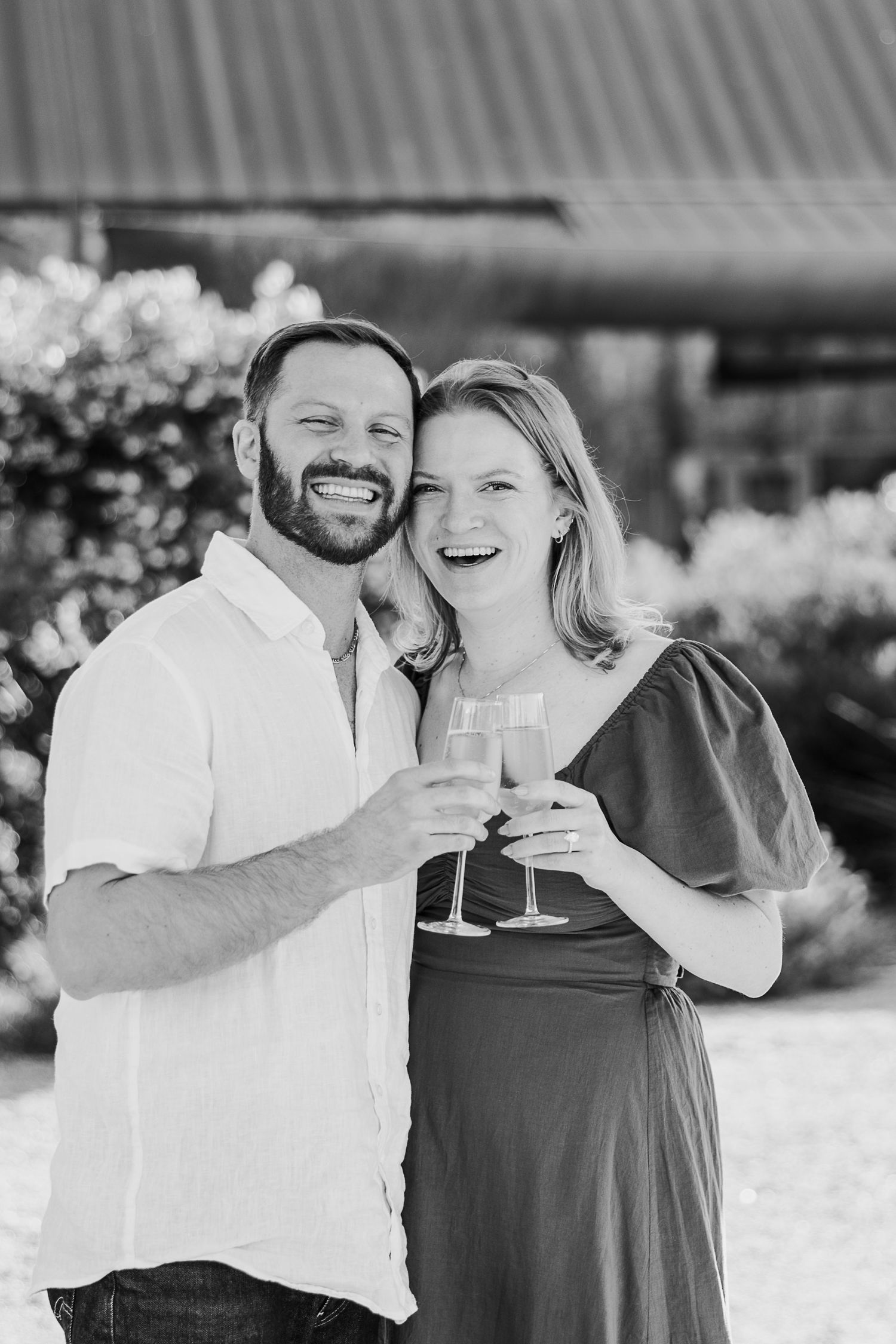 A couple shares a joyful moment together outdoors in black and white photography.