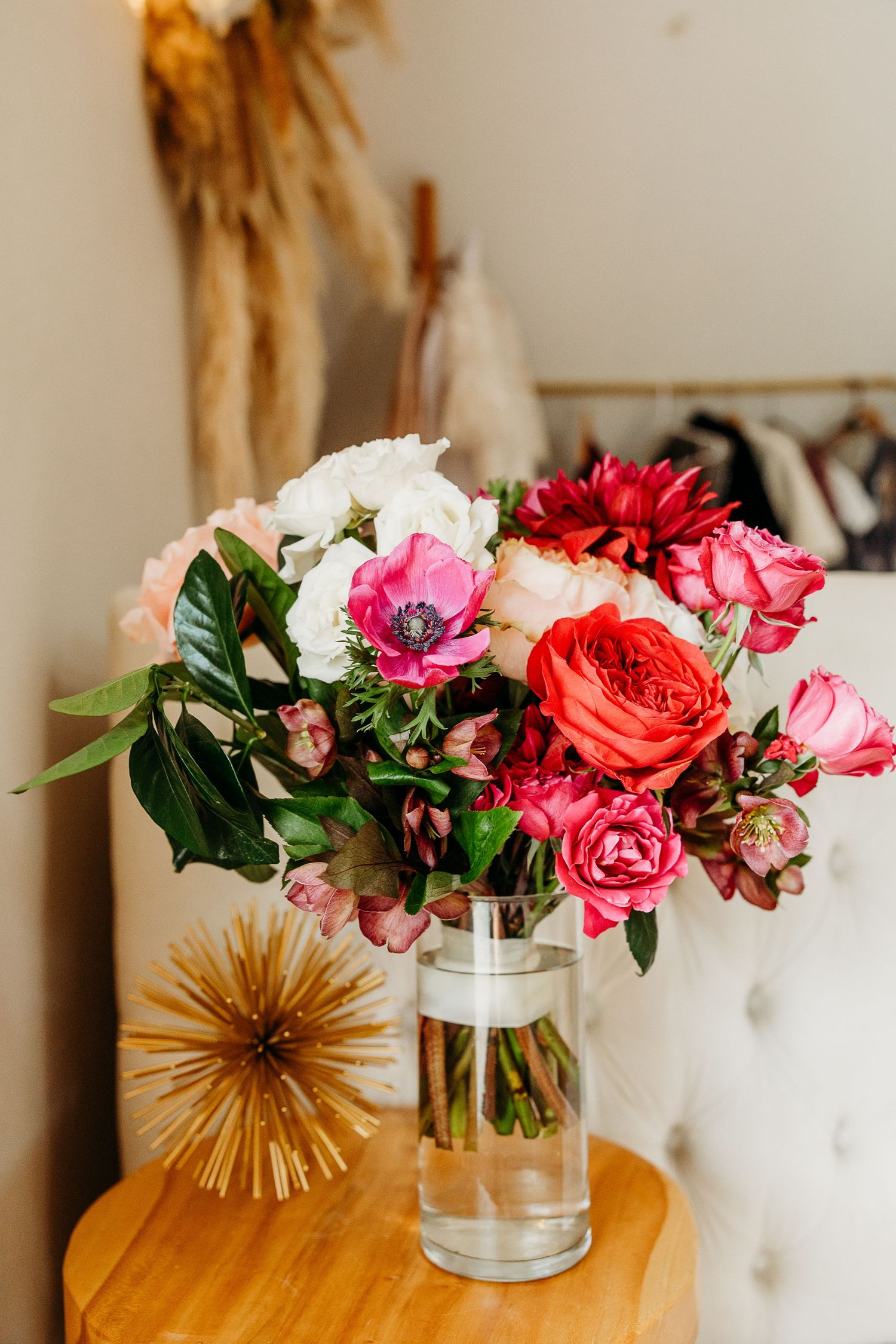 Elegant floral arrangement with pink and red roses in glass vases displayed on a wooden surface with golden decor.