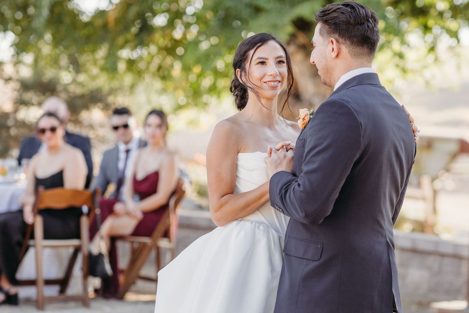 Romantic couple dancing together outdoors in a garden setting during a wedding celebration.