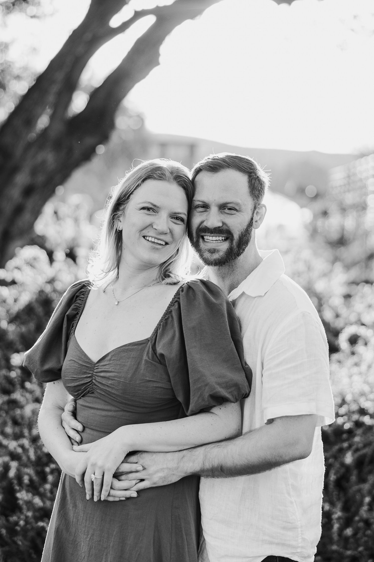 A joyful black and white portrait of a couple sharing intimate moments outdoors.