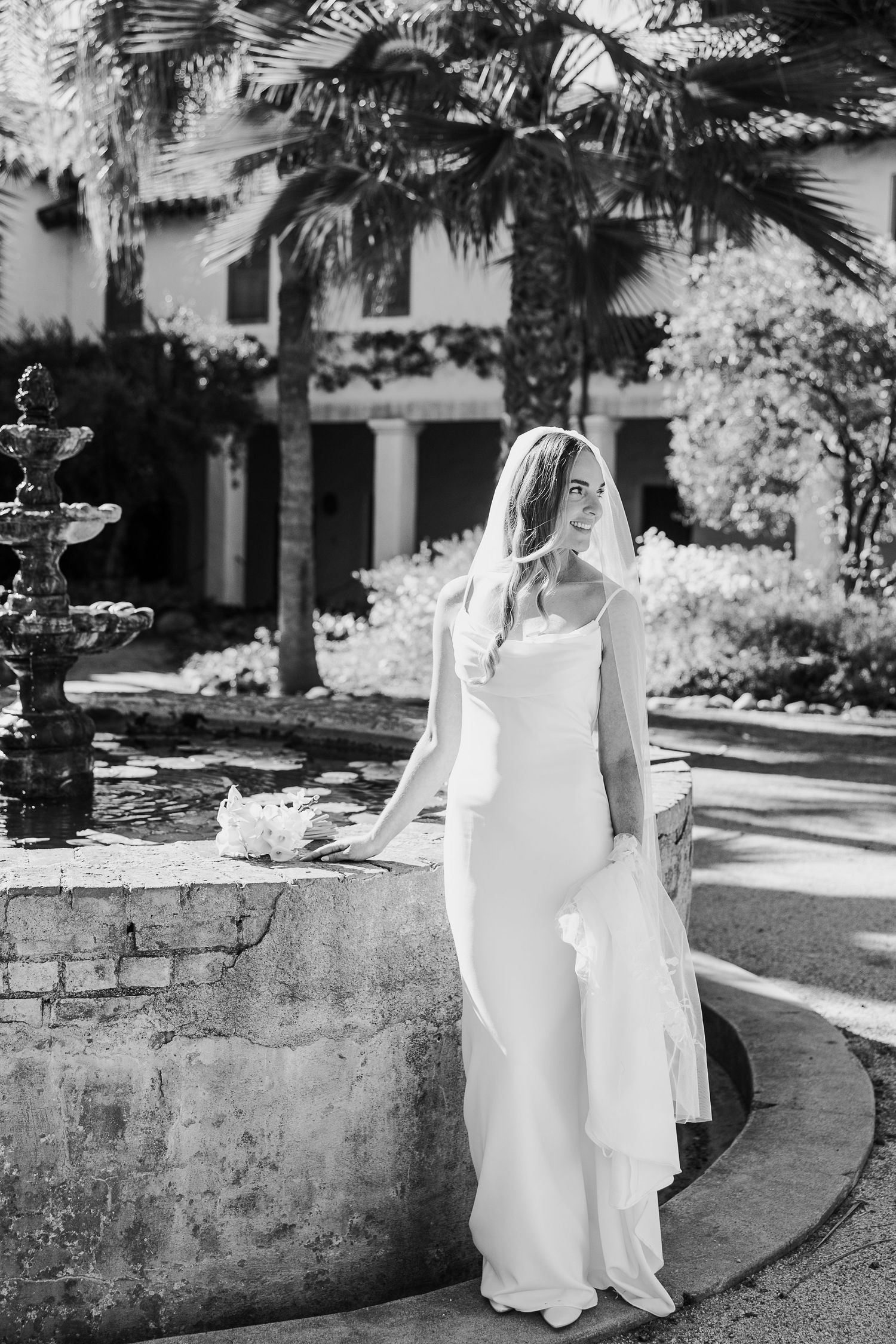 Black and white photo series showing the flowing movement of a white dress against a stone wall in an outdoor setting.