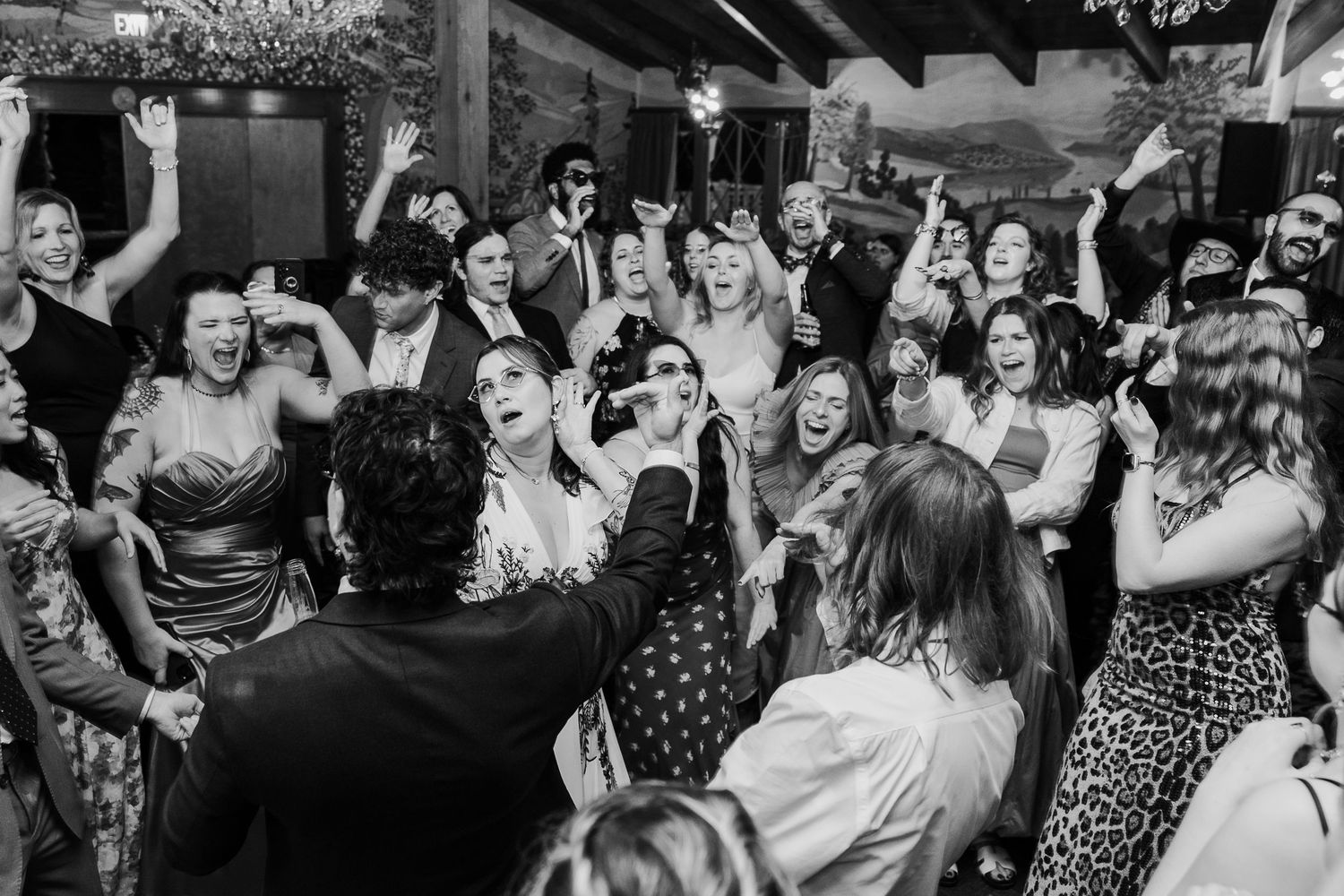 Black and white photo of wedding reception dance party with crowd celebrating.