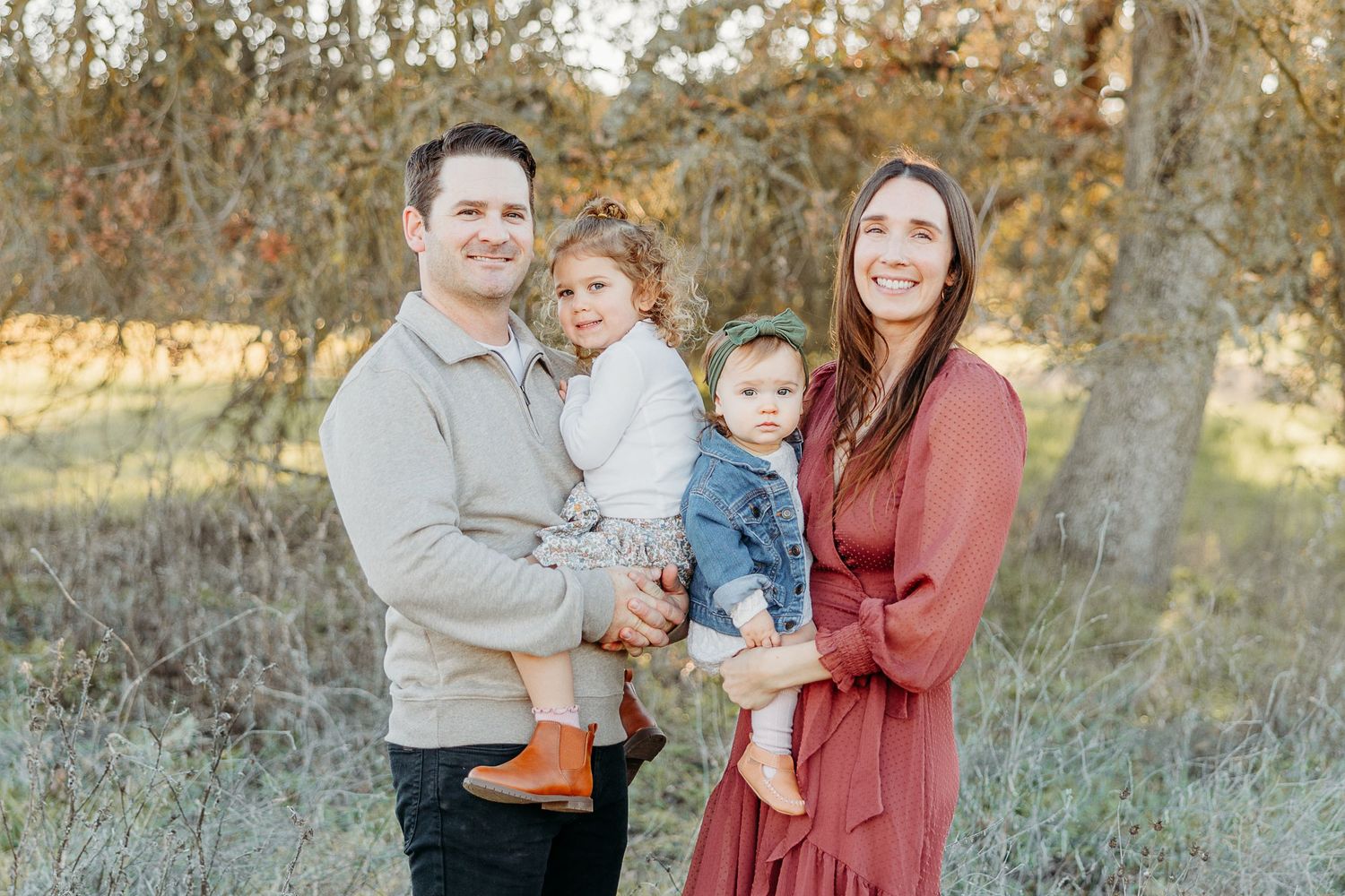 Family portrait session in a golden autumn field with natural lighting.