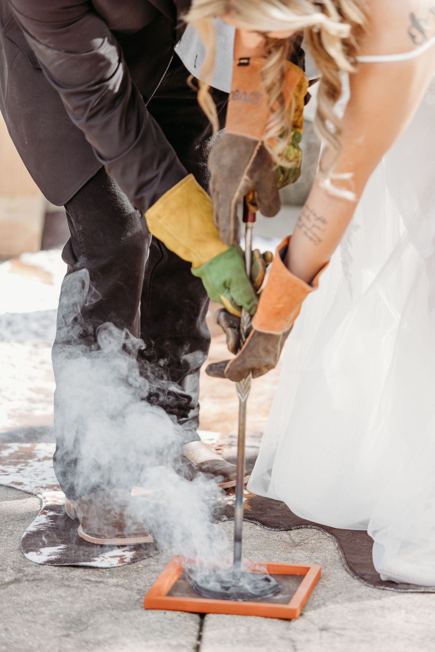 A couple in wedding attire cooperates to pour smoking liquid nitrogen during their ceremony.
