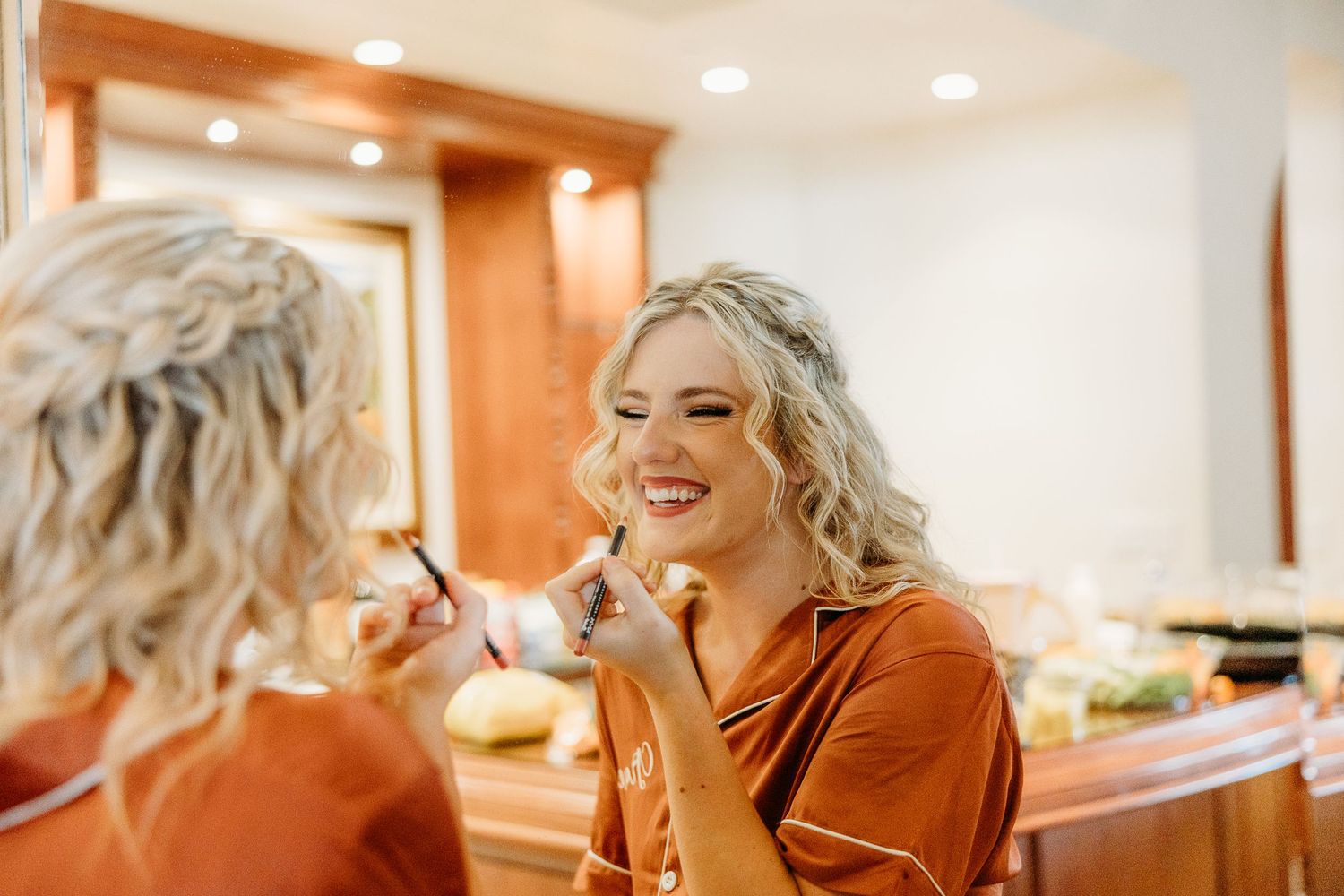 Wedding preparation scene with someone getting their makeup done in a warm-lit room.