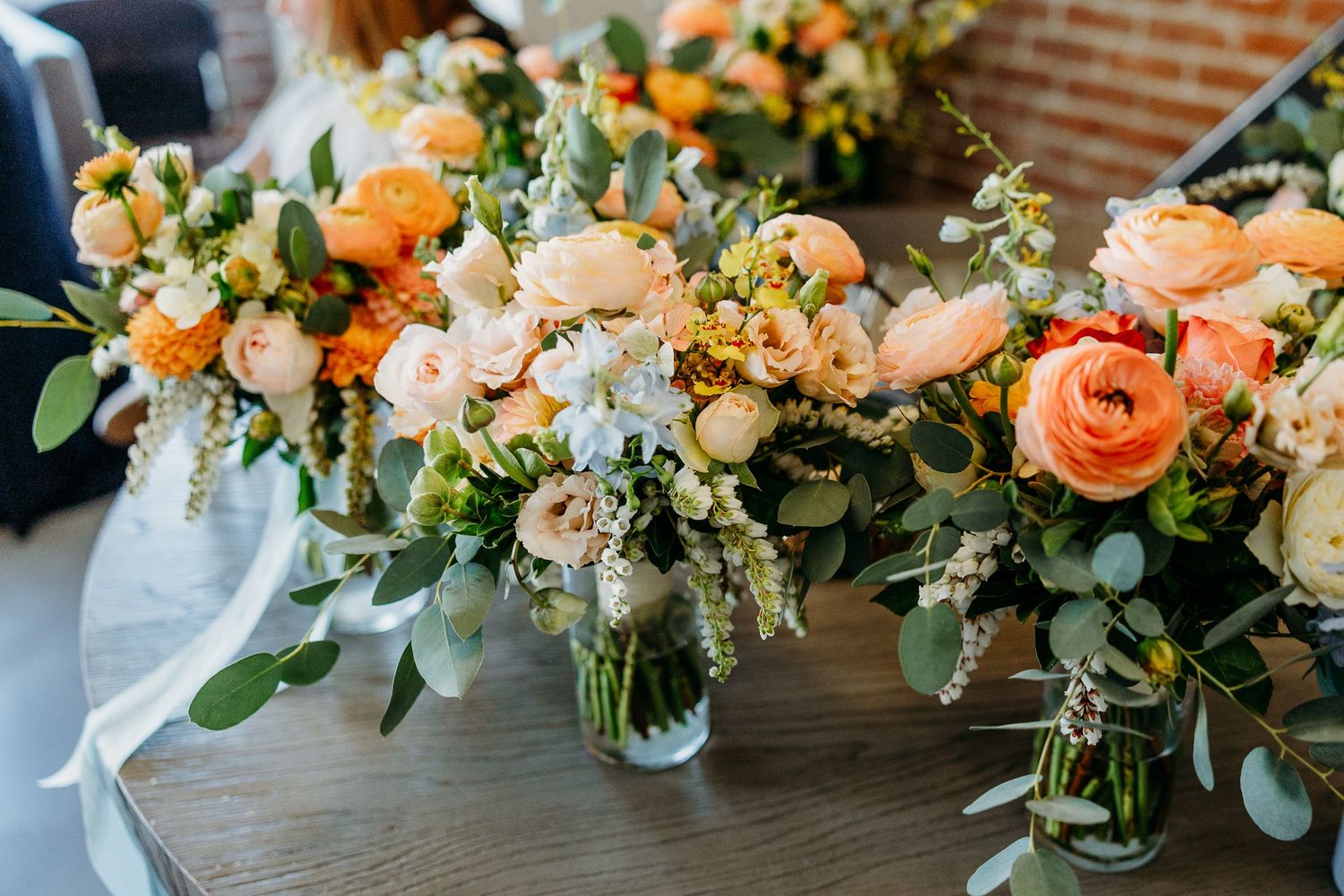 Elegant floral centerpieces with peach roses and greenery arranged in glass vases.