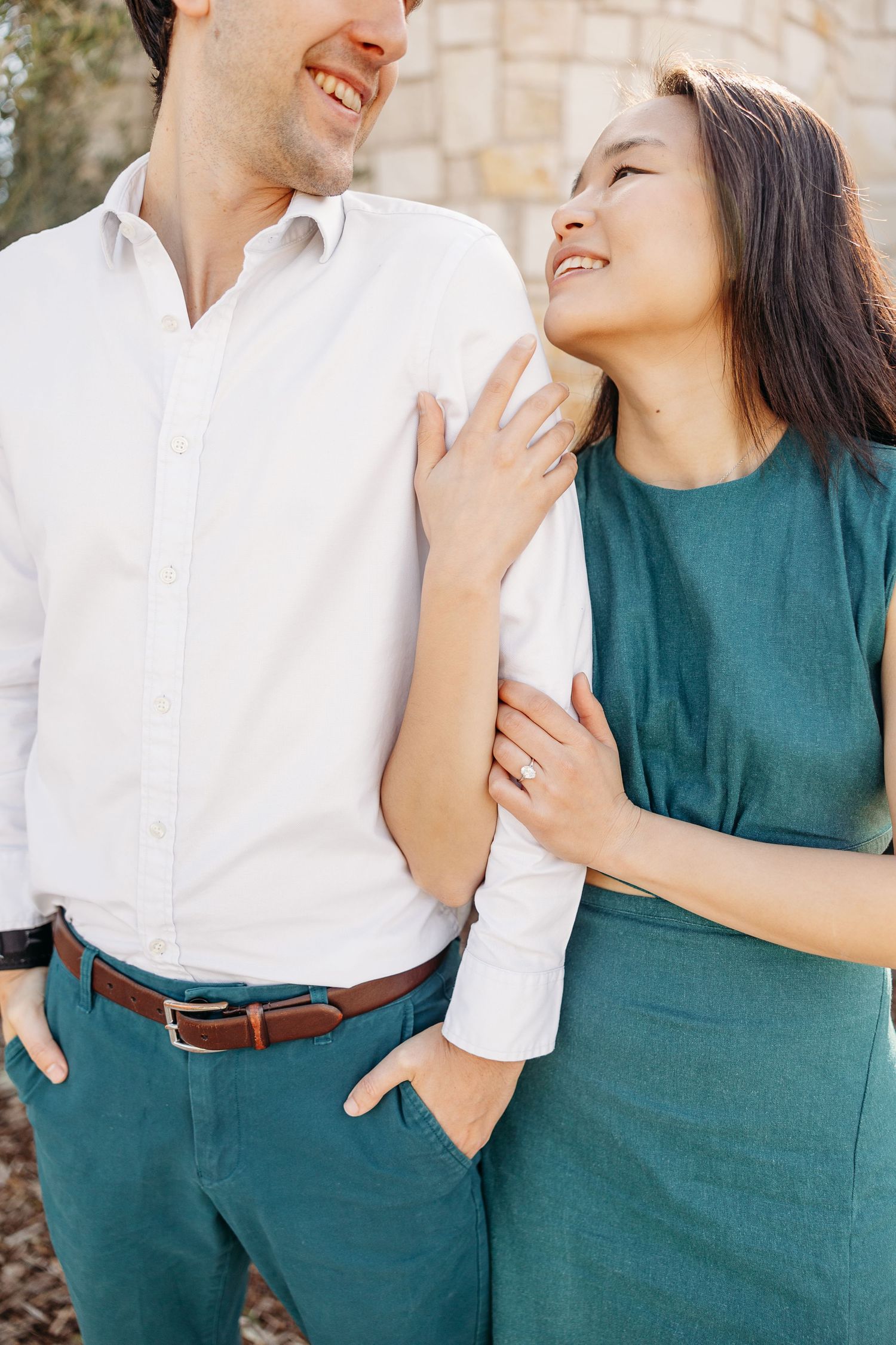 Happy couple in matching teal and white outfits sharing an intimate moment while laughing together outdoors.