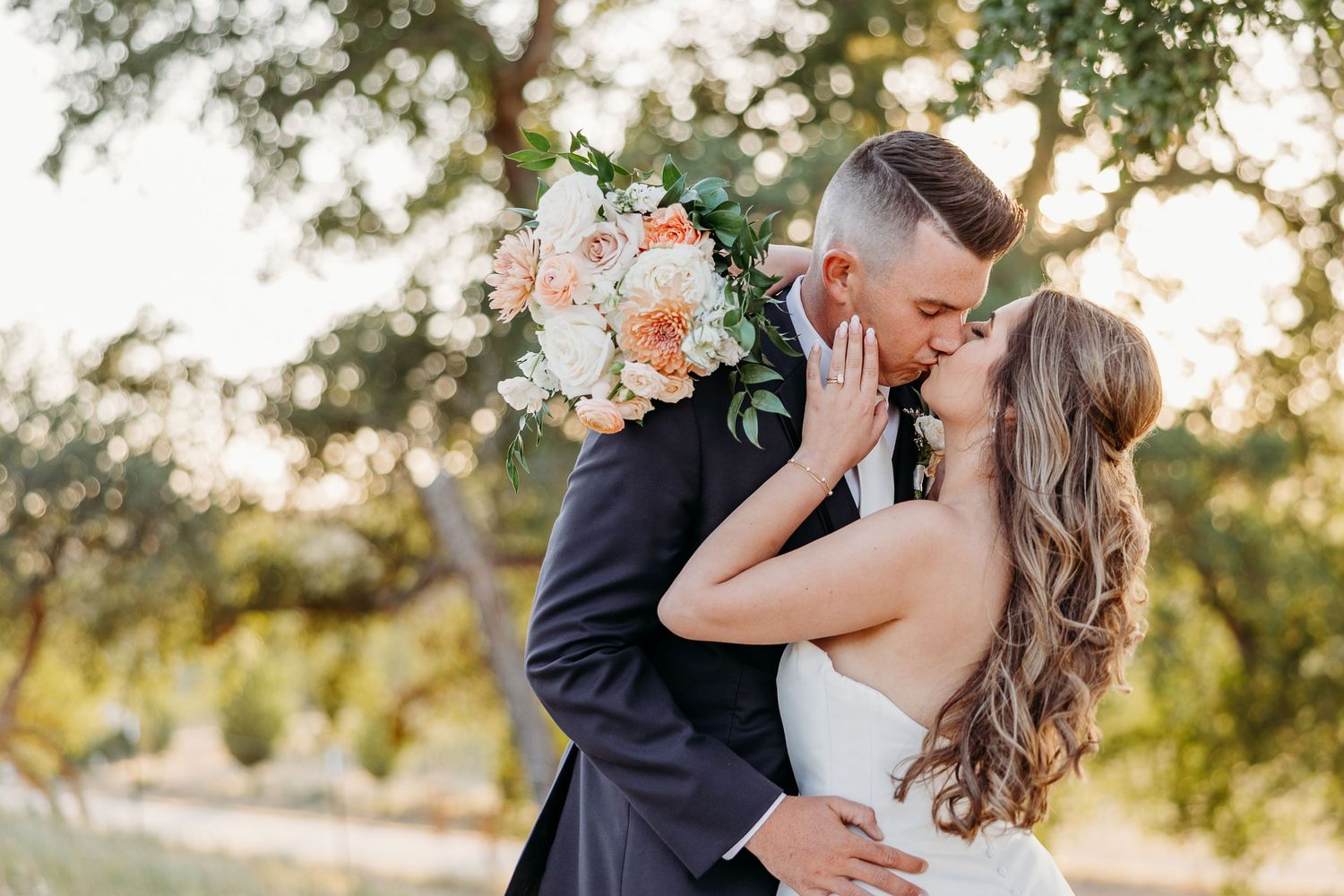 Outdoor sunset wedding photos feature a bride in white dress with soft romantic lighting and floral accents.