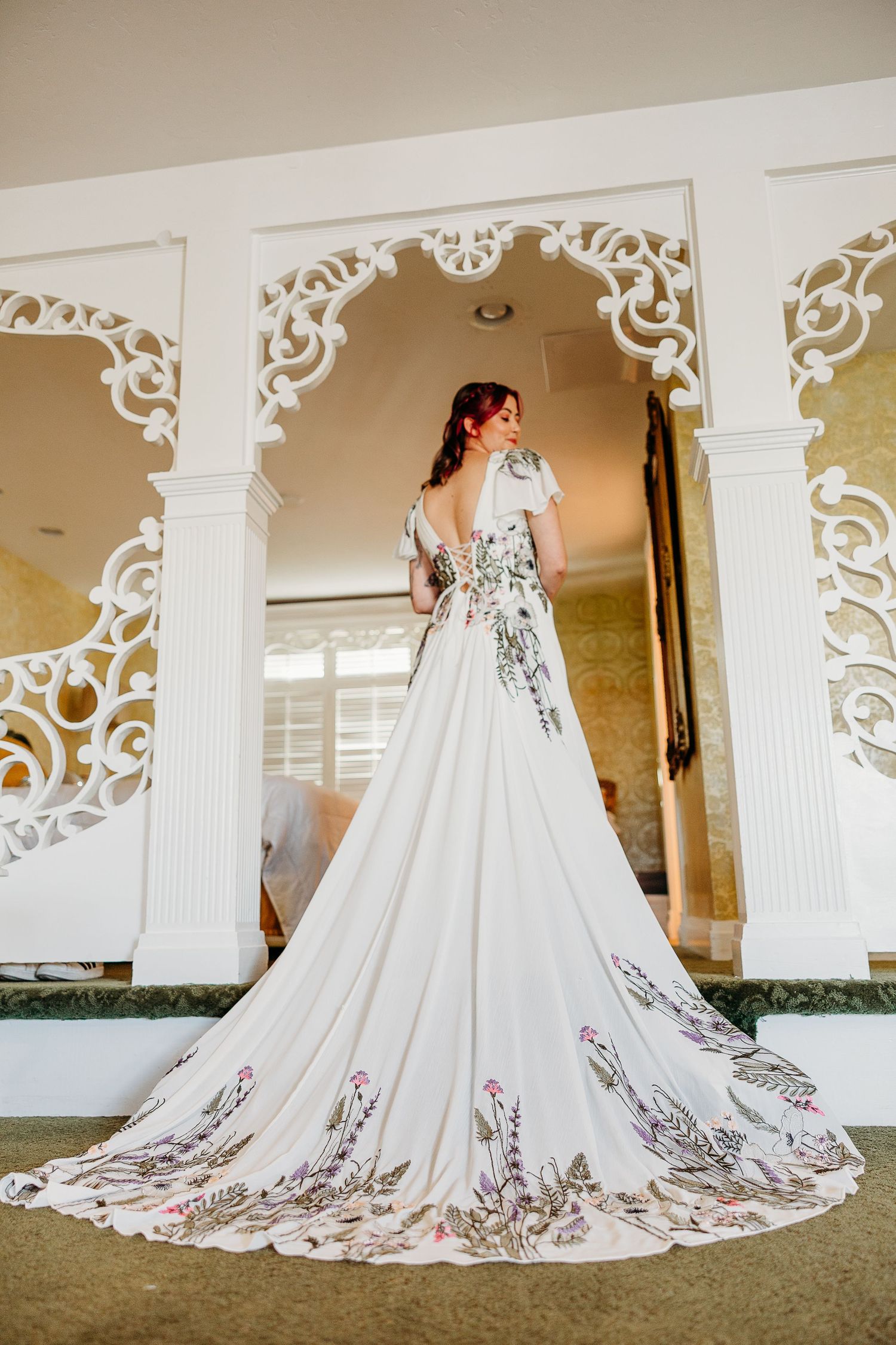 A stunning white wedding gown with intricate embroidery details and a dramatic cathedral train displayed in a series of photos.
