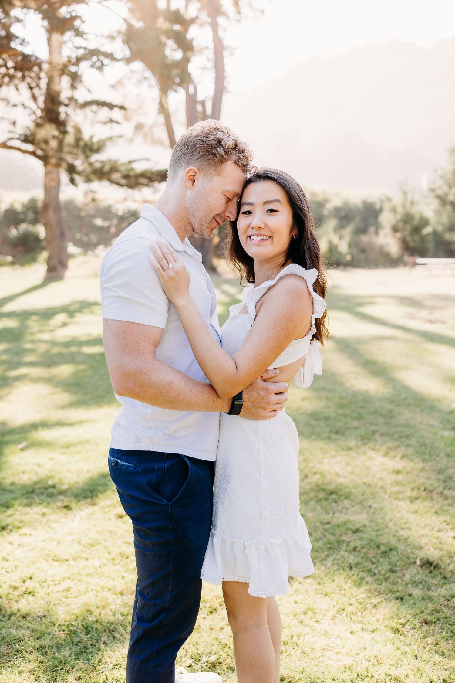Happy couple in white and blue sharing a romantic moment outdoors.