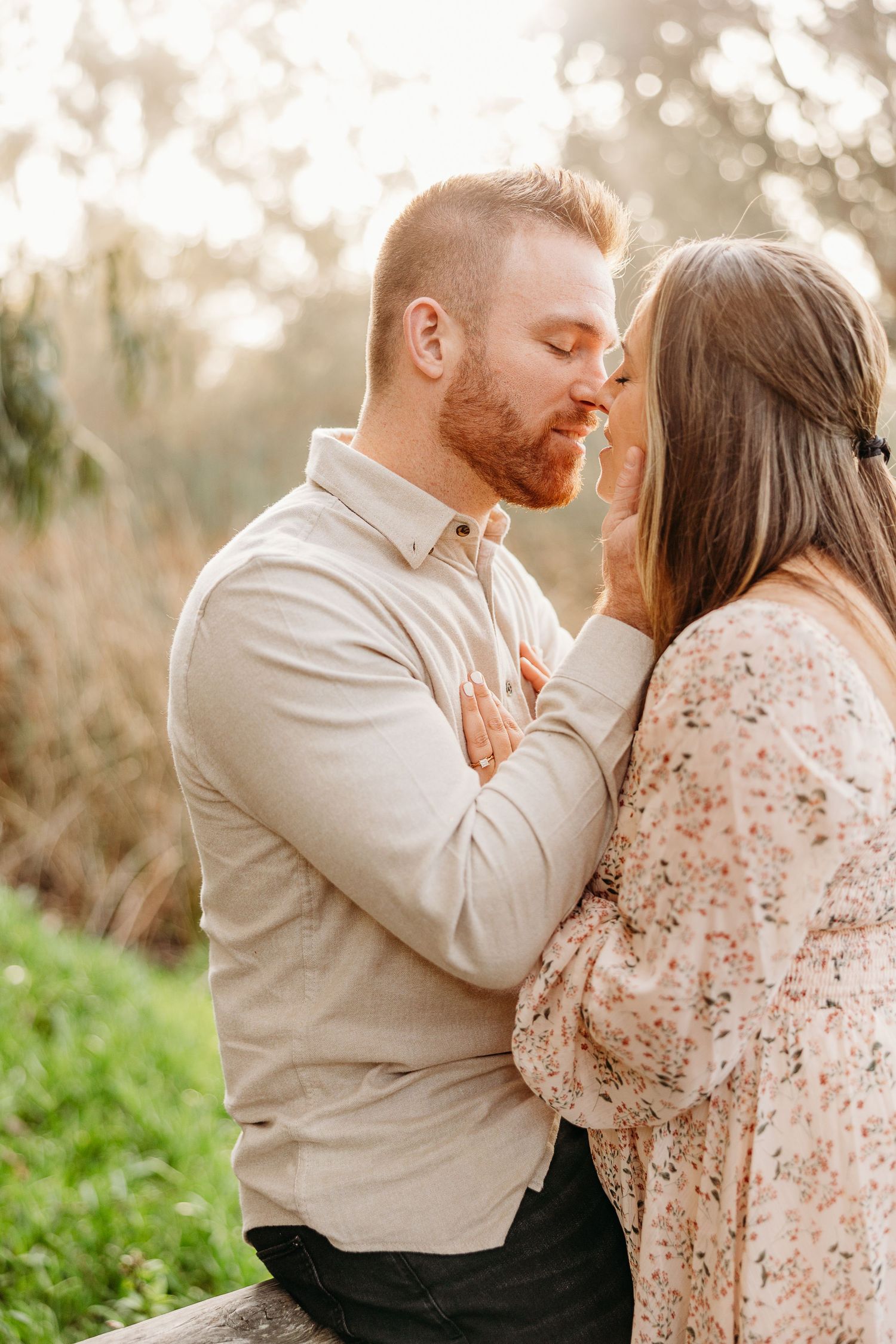A romantic couple shares an intimate moment in nature during golden hour sunset.