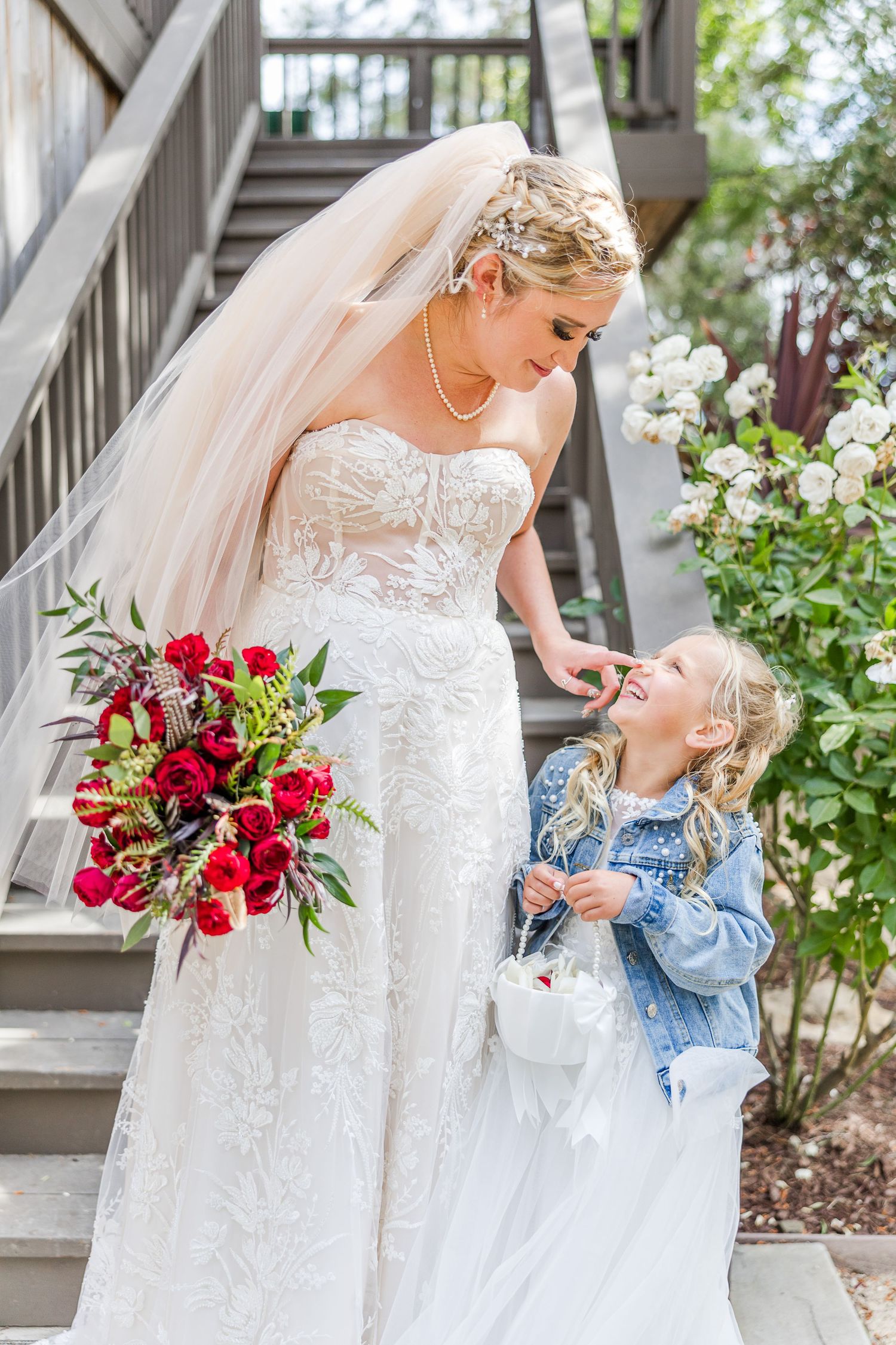 An enchanting wedding moment captured on stairs with a flowergirl in denim jacket.