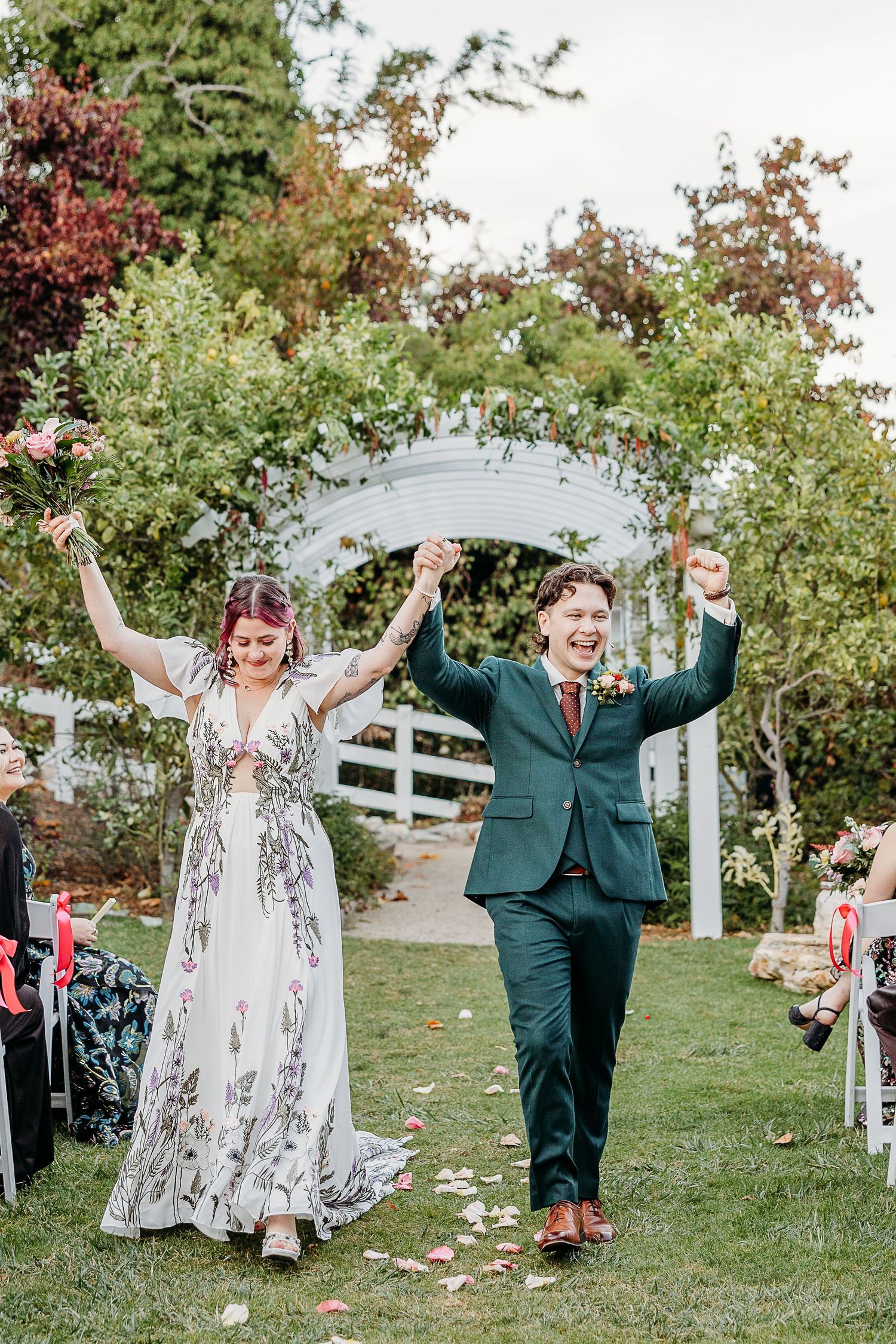 Celebratory moment on a lawn with white chairs and autumn foliage in the background.