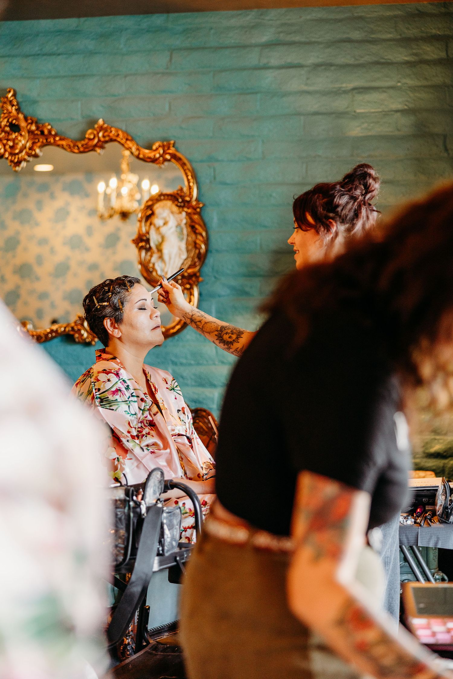 Ornate gold-framed mirror reflects a celebratory scene in a room with turquoise walls.