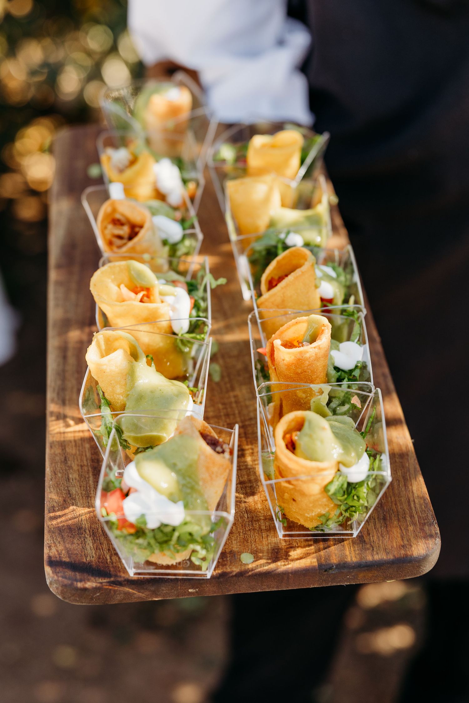 Elegant appetizers served in small glass dishes on a rustic wooden board with garnish.