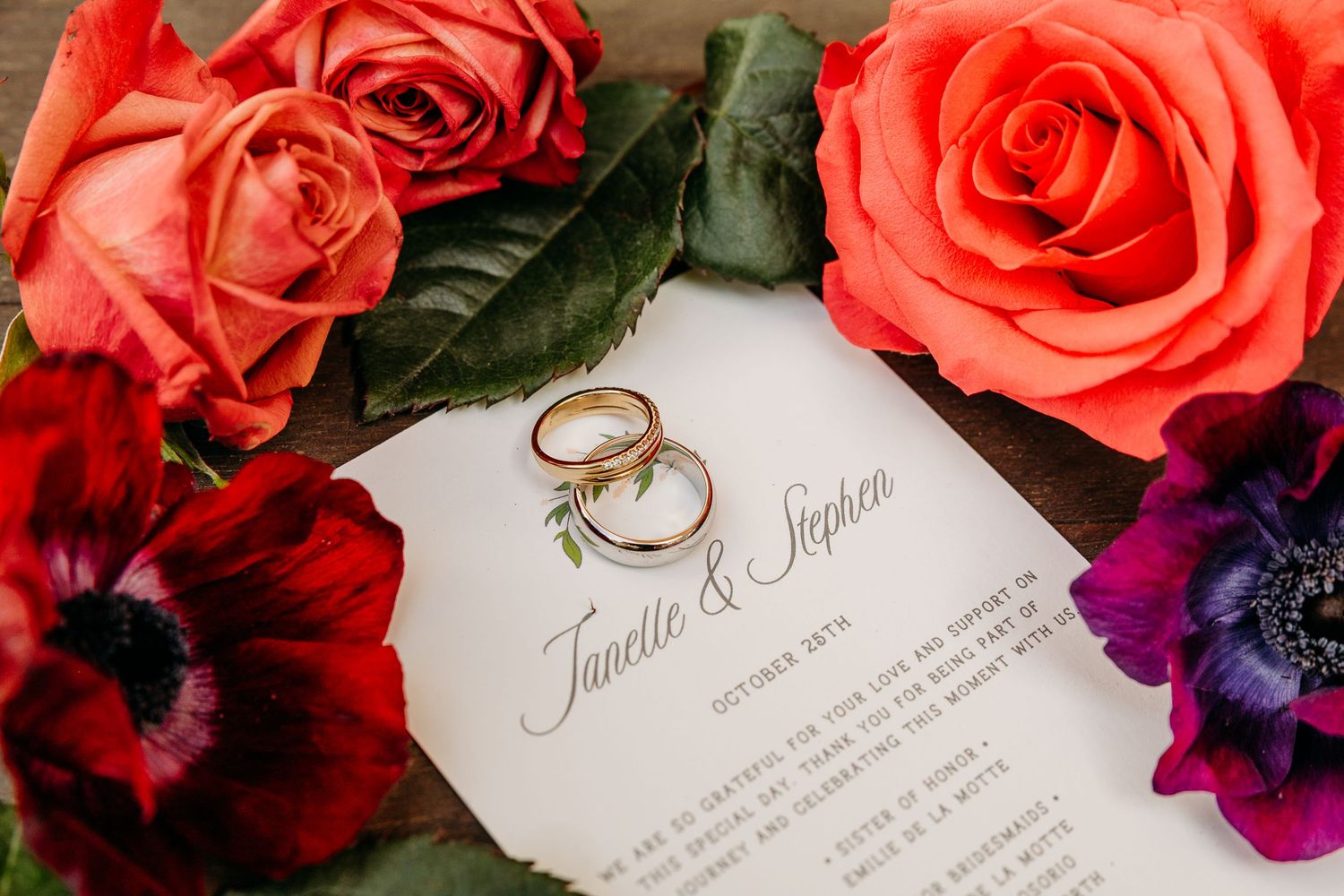 Wedding invitation with coral roses and wedding rings arranged artistically.