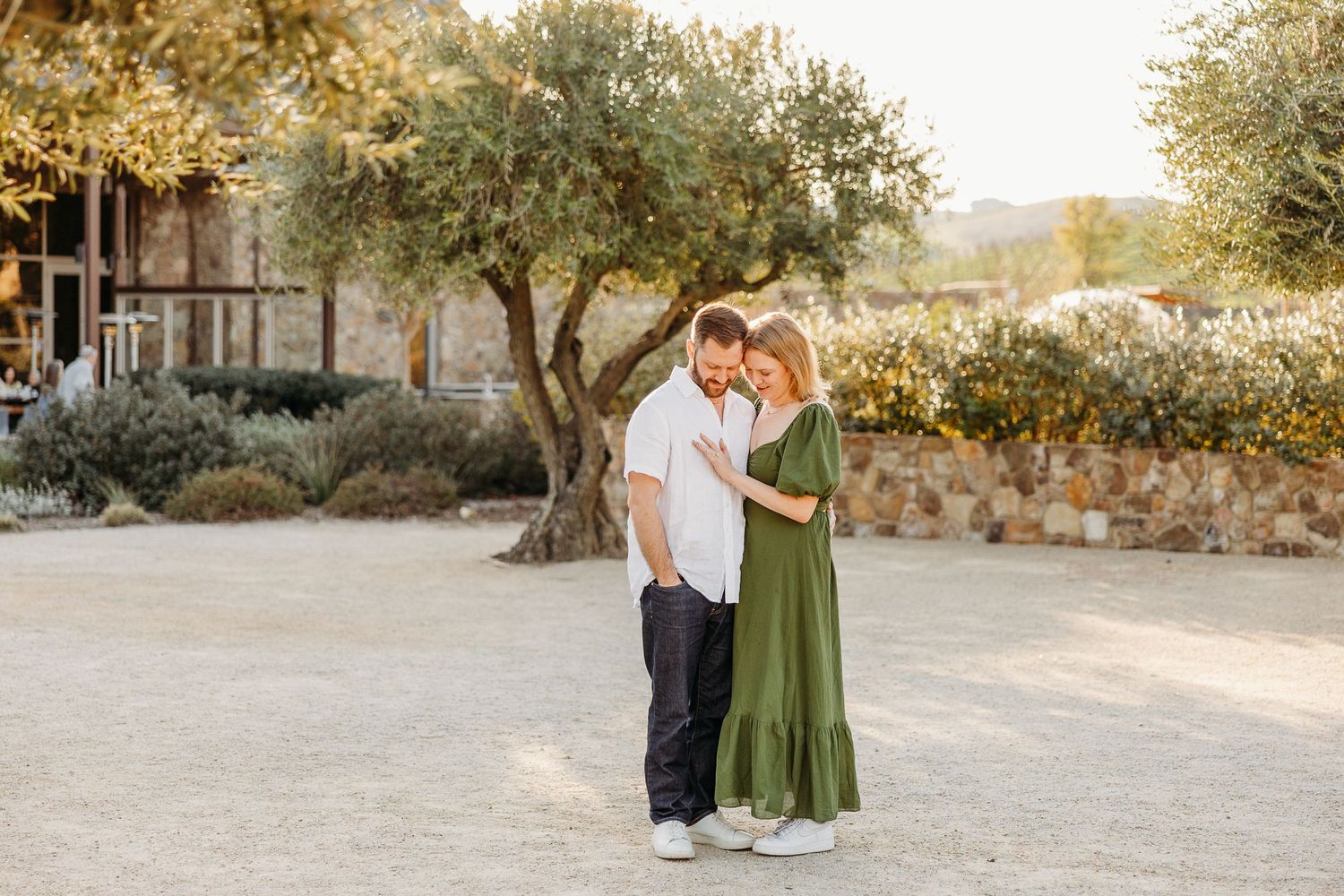 A couple walks together through a sun-drenched outdoor setting during a romantic photo session.