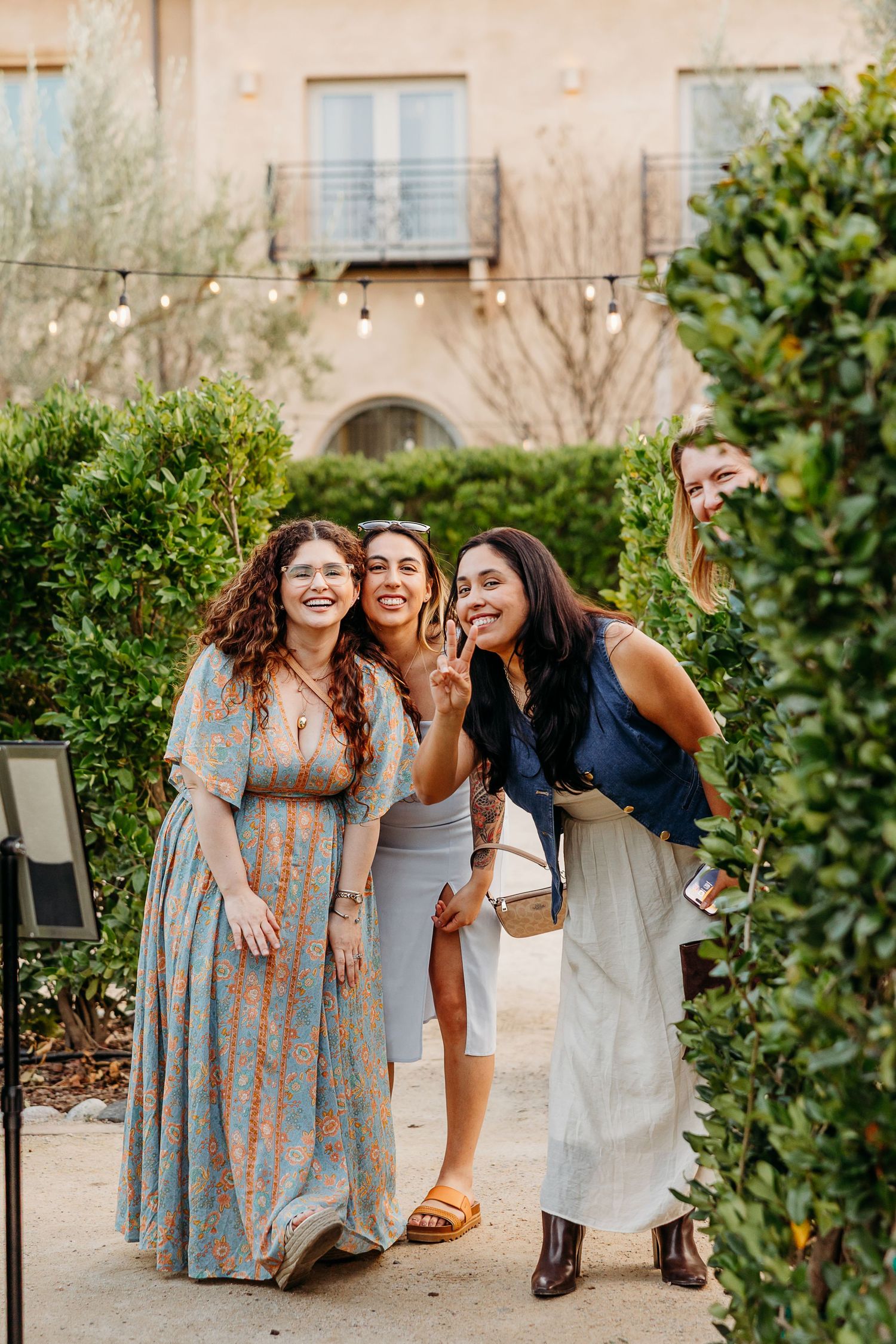 Candid moment of friends laughing together and smiling for the photographer in a garden setting.