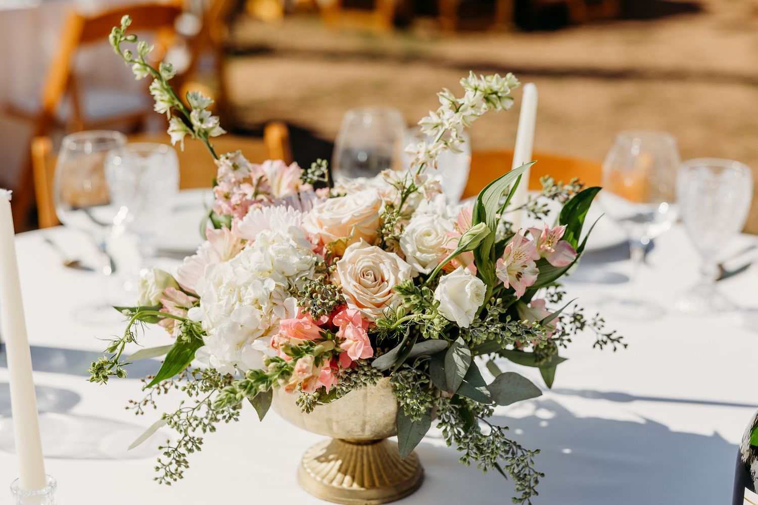 Elegant floral centerpieces with white and pink flowers arranged on tables at a wedding reception.