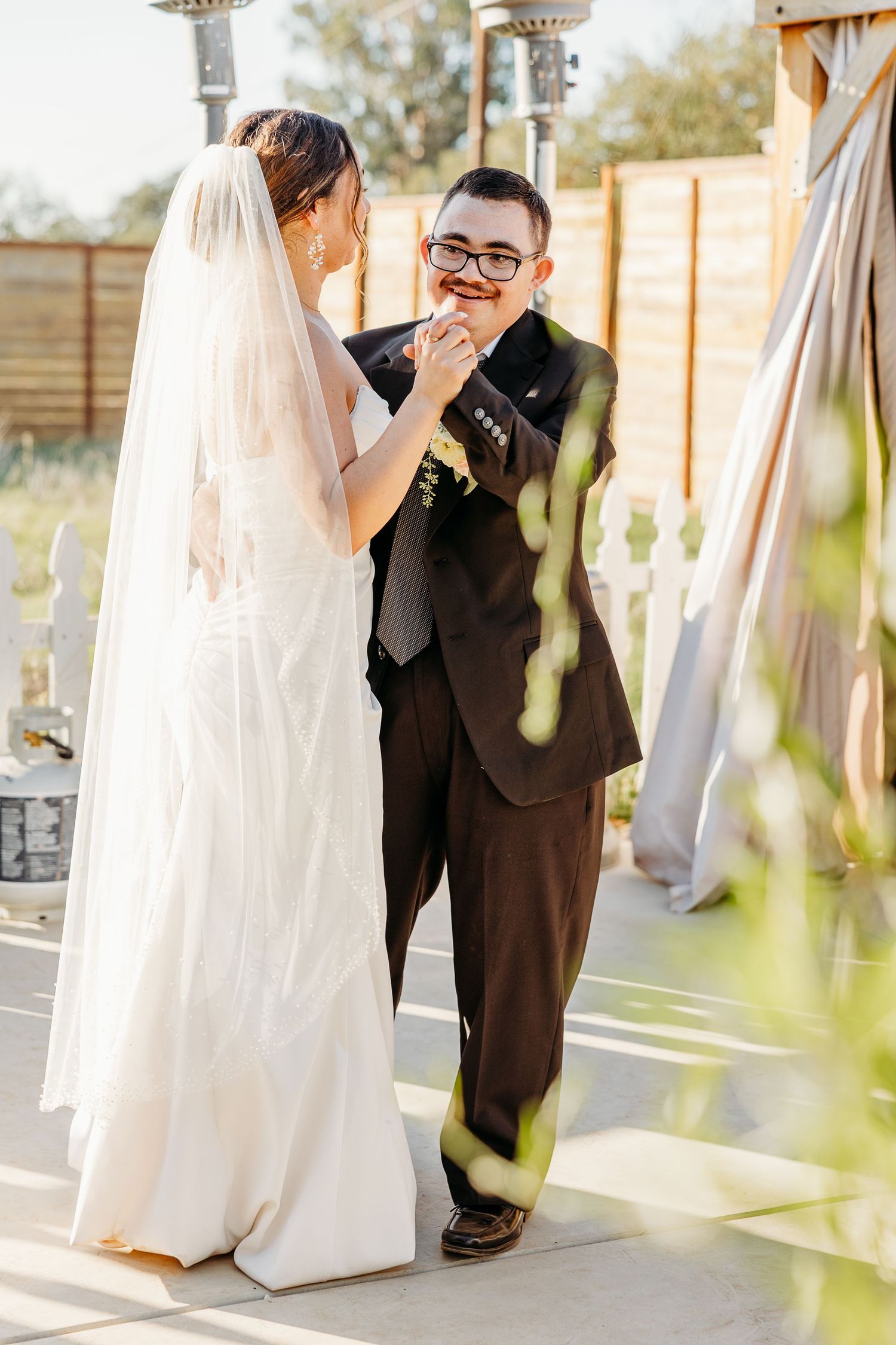 A tender moment between newlyweds as the bride touches the groom's face under outdoor lighting.