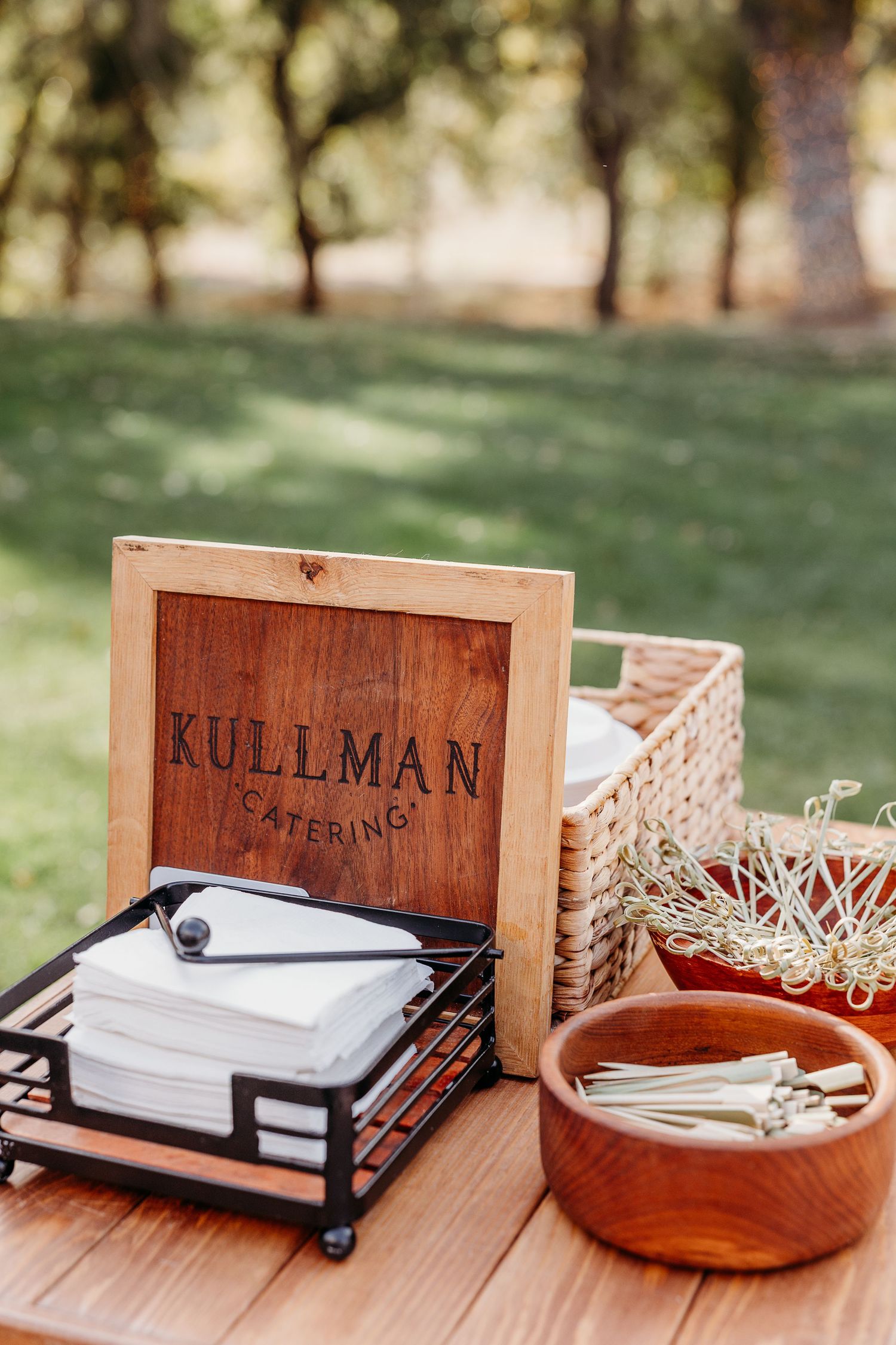 Wooden box labeled Kullman with paper supplies and decorative accessories on outdoor table.