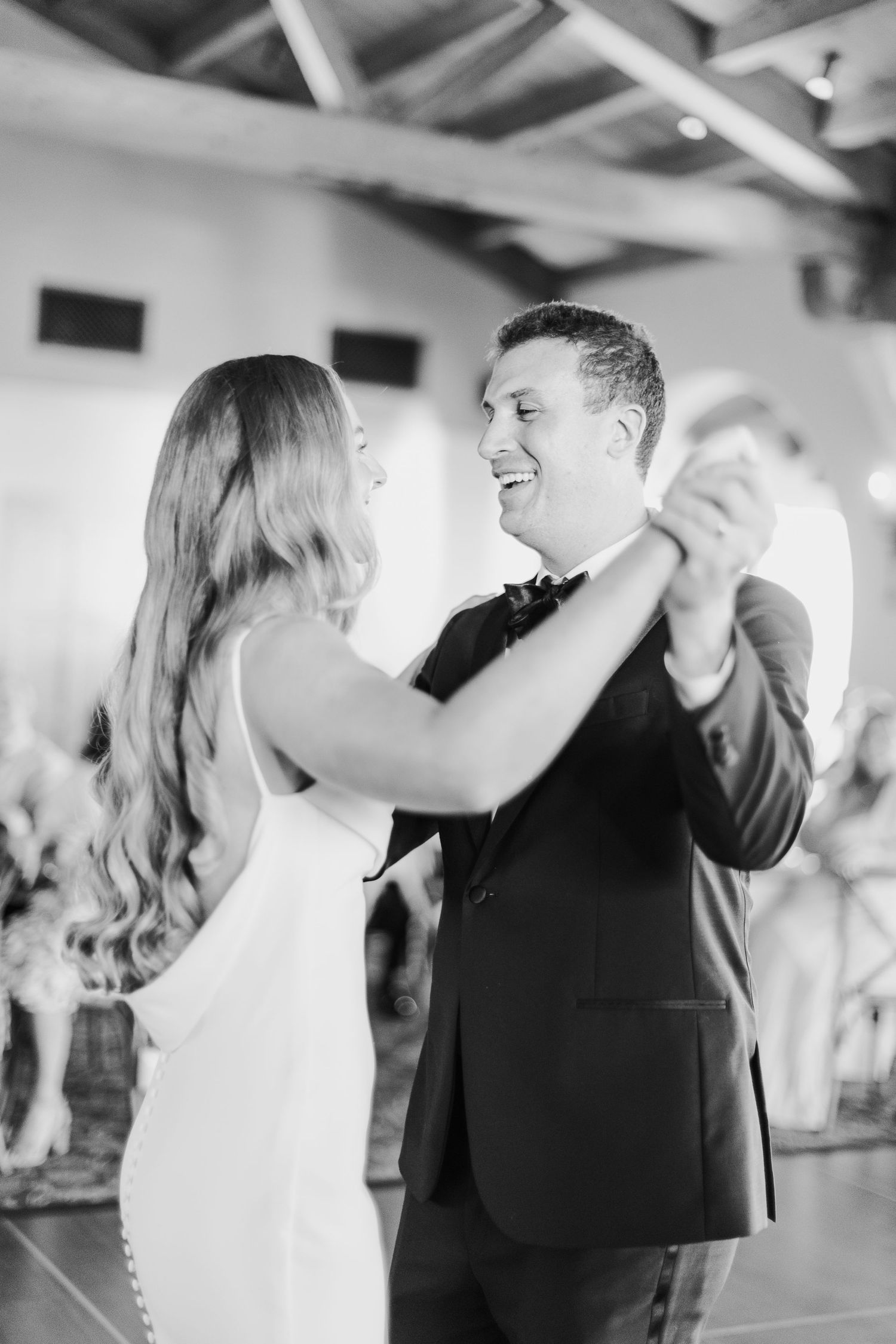 Wedding guests dancing and celebrating on a dance floor at an indoor reception venue.