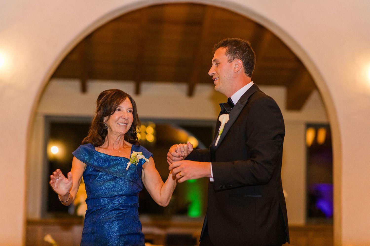A couple sharing a dance moment under an arched doorway at their wedding reception.