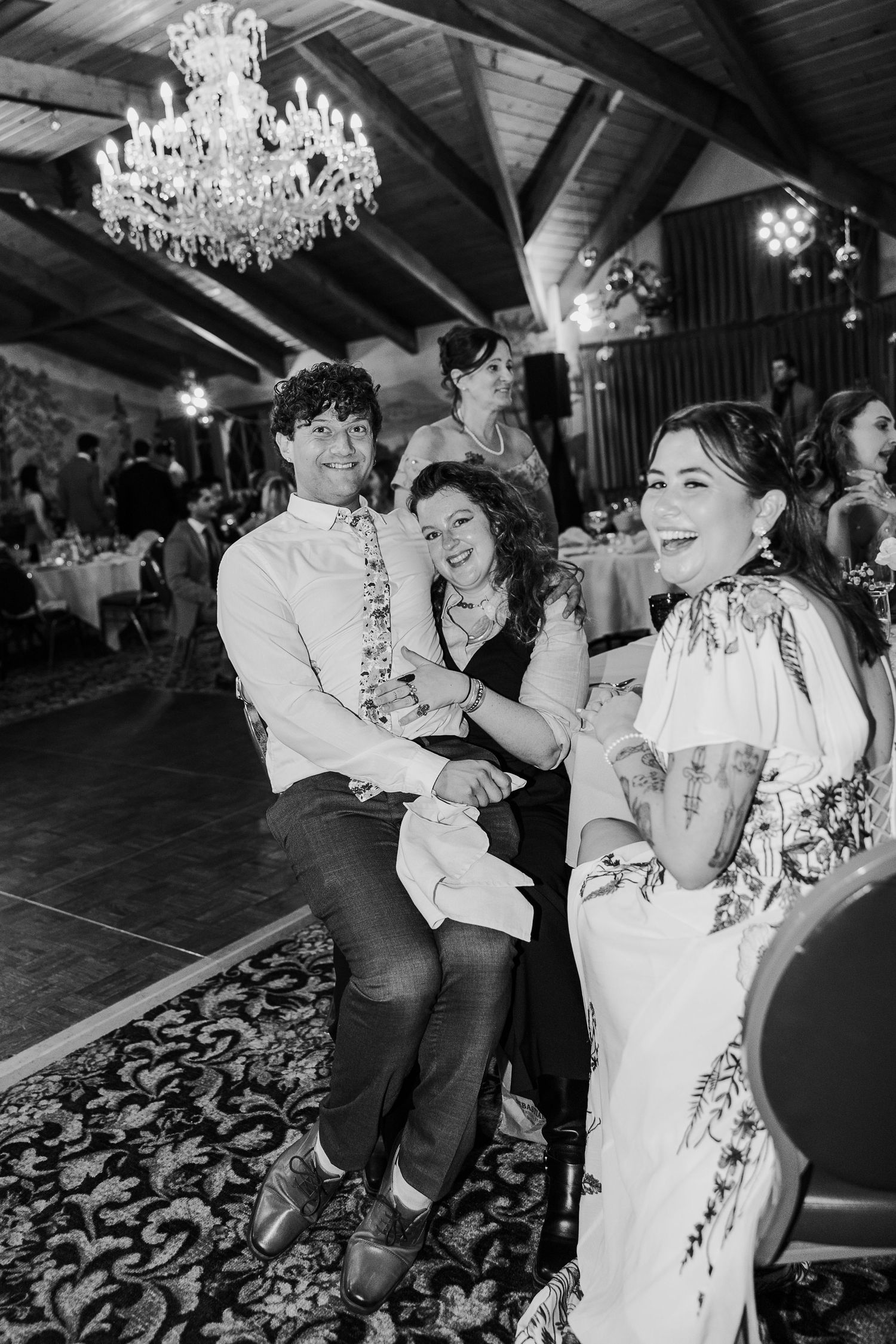 A sequence of black and white photos showing joyful dancing at a wedding reception under elegant chandeliers.
