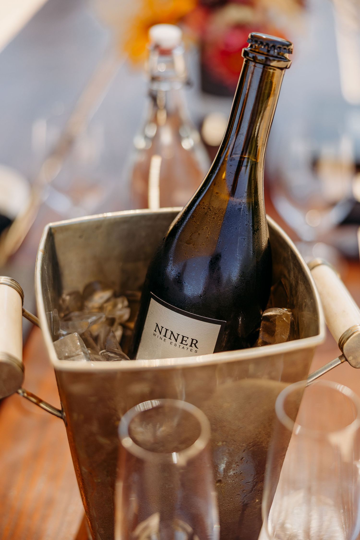 Wine bottles chilling in silver ice buckets at an elegant event.