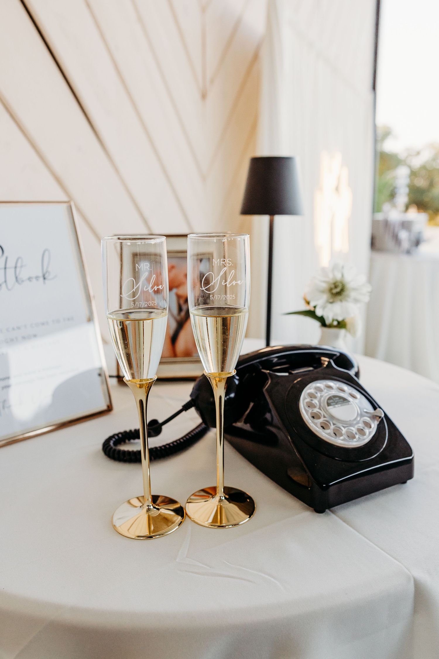 Vintage black rotary phone and champagne glasses arranged on a white table with elegant wedding decor.