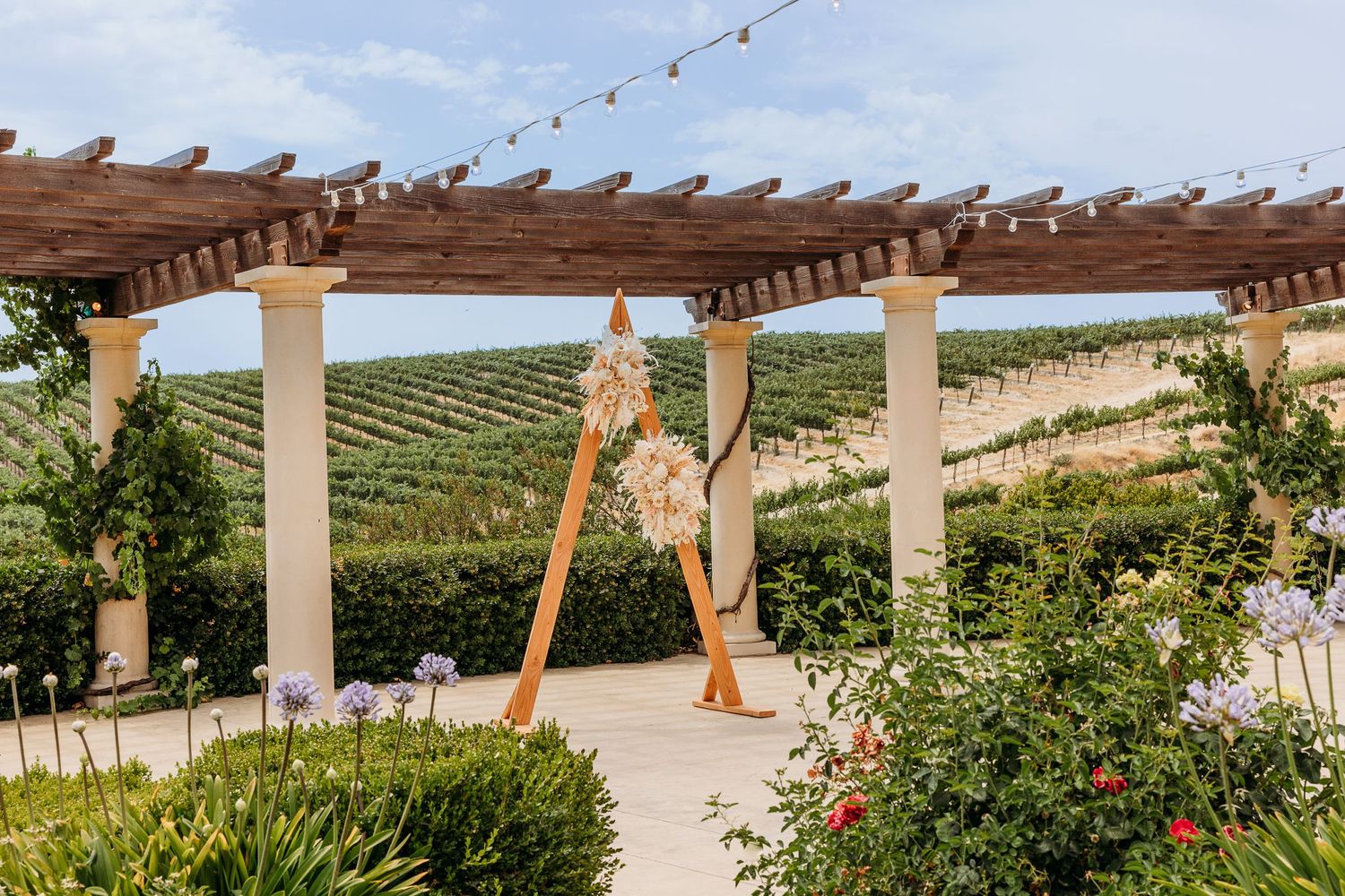 Wedding venue pergola with string lights overlooking scenic vineyard hills.
