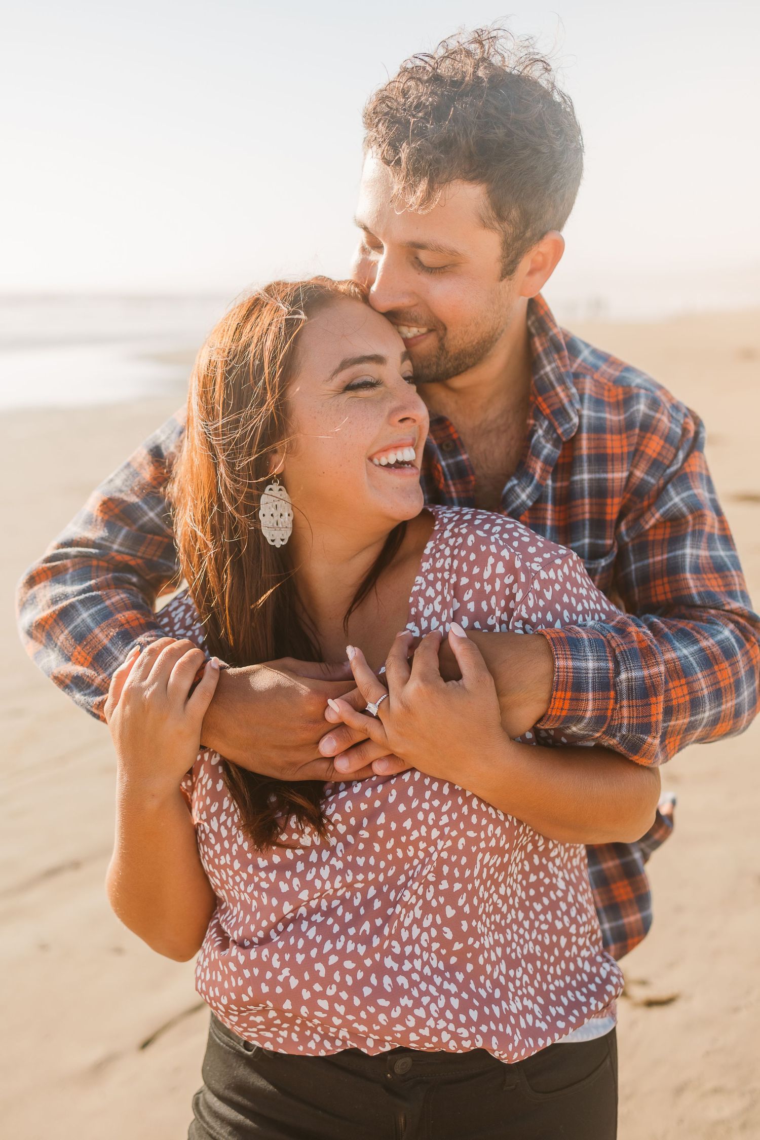 A couple shares a joyful moment together on a sunny beach.