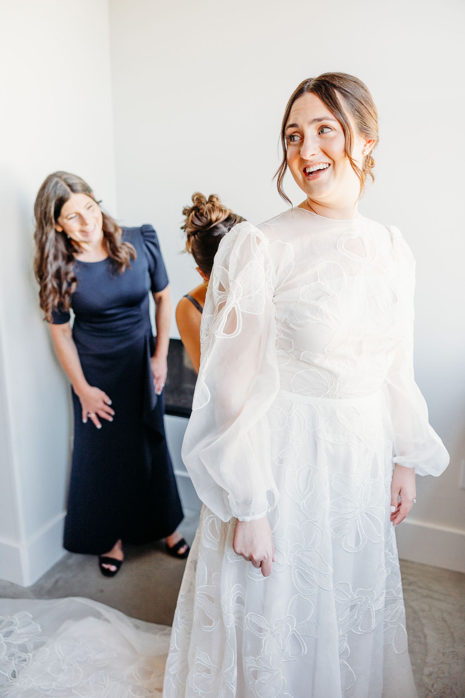 A beautiful wedding preparation scene with elegant white dress and joyful expressions in a suite at Hotel Cerro San Luis Obispo.