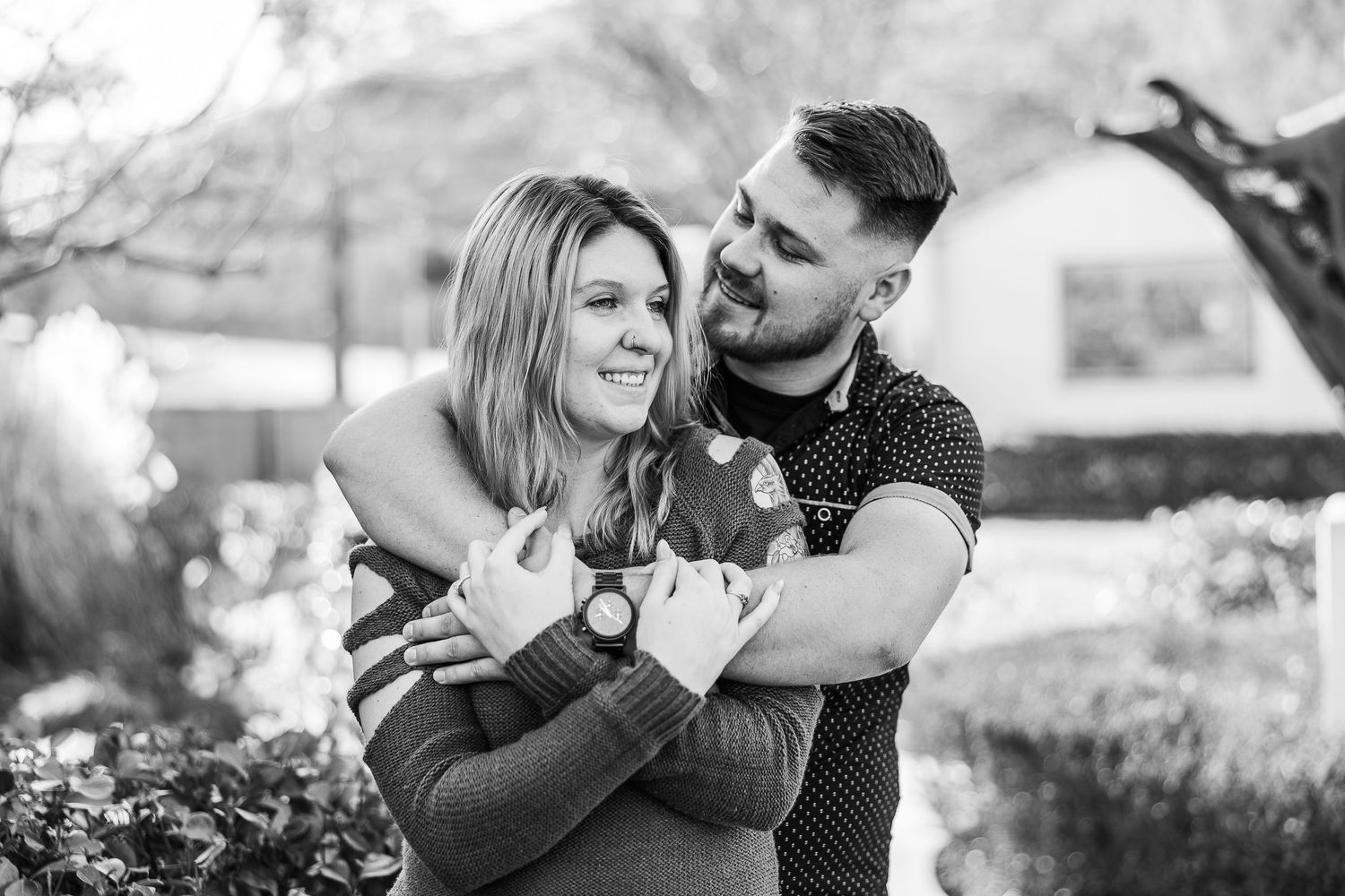 Black and white portrait of couple sharing tender moment in garden landscape.