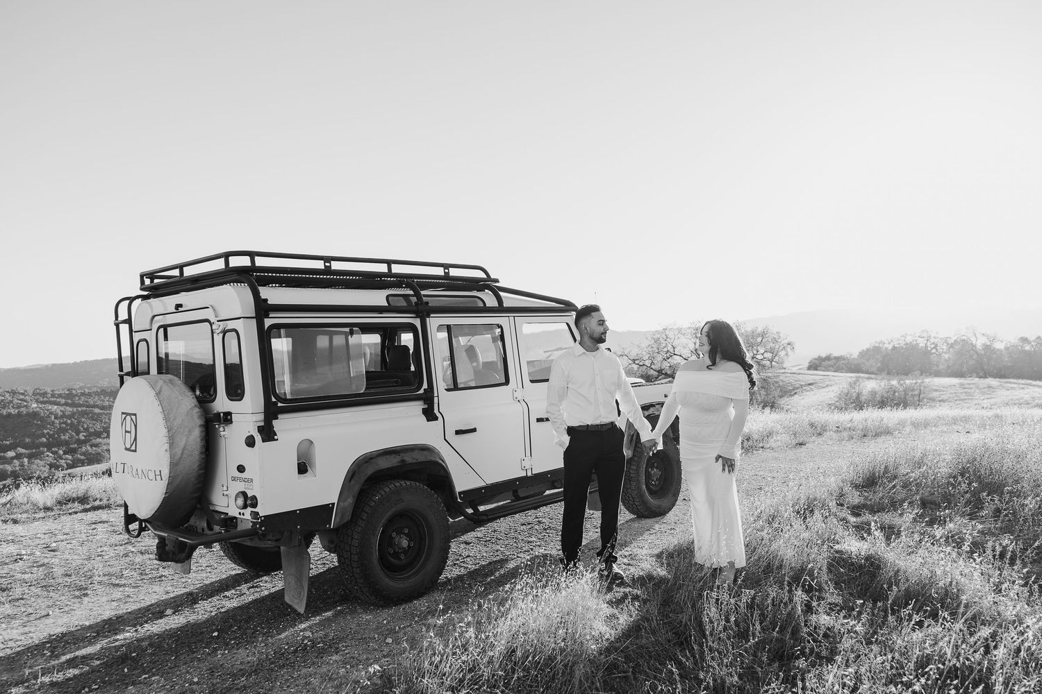 Black and white photo of vintage Land Rover parked in rugged terrain during outdoor adventure.