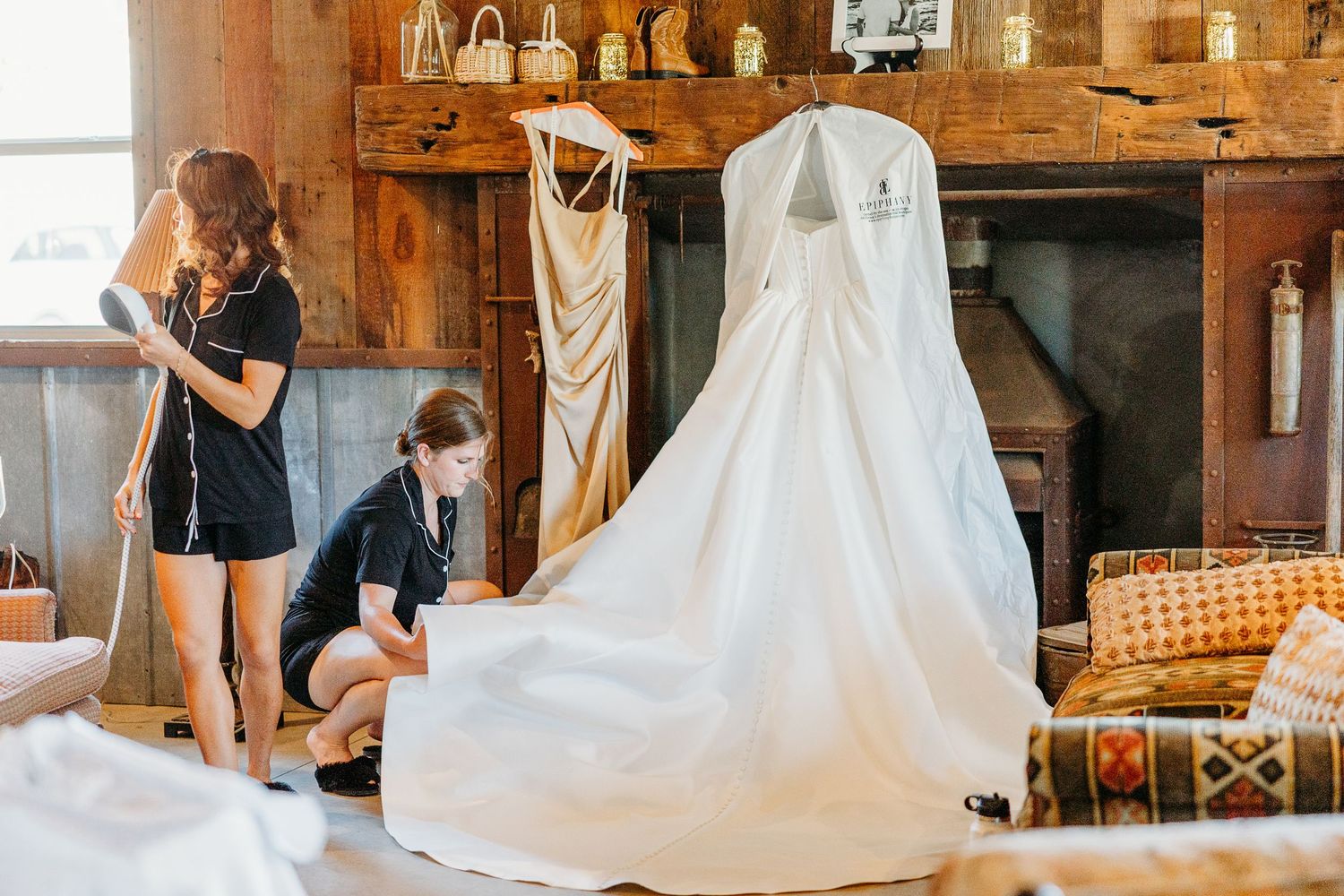 Wedding dresses hang elegantly in a rustic barn venue while being prepared for a special celebration.