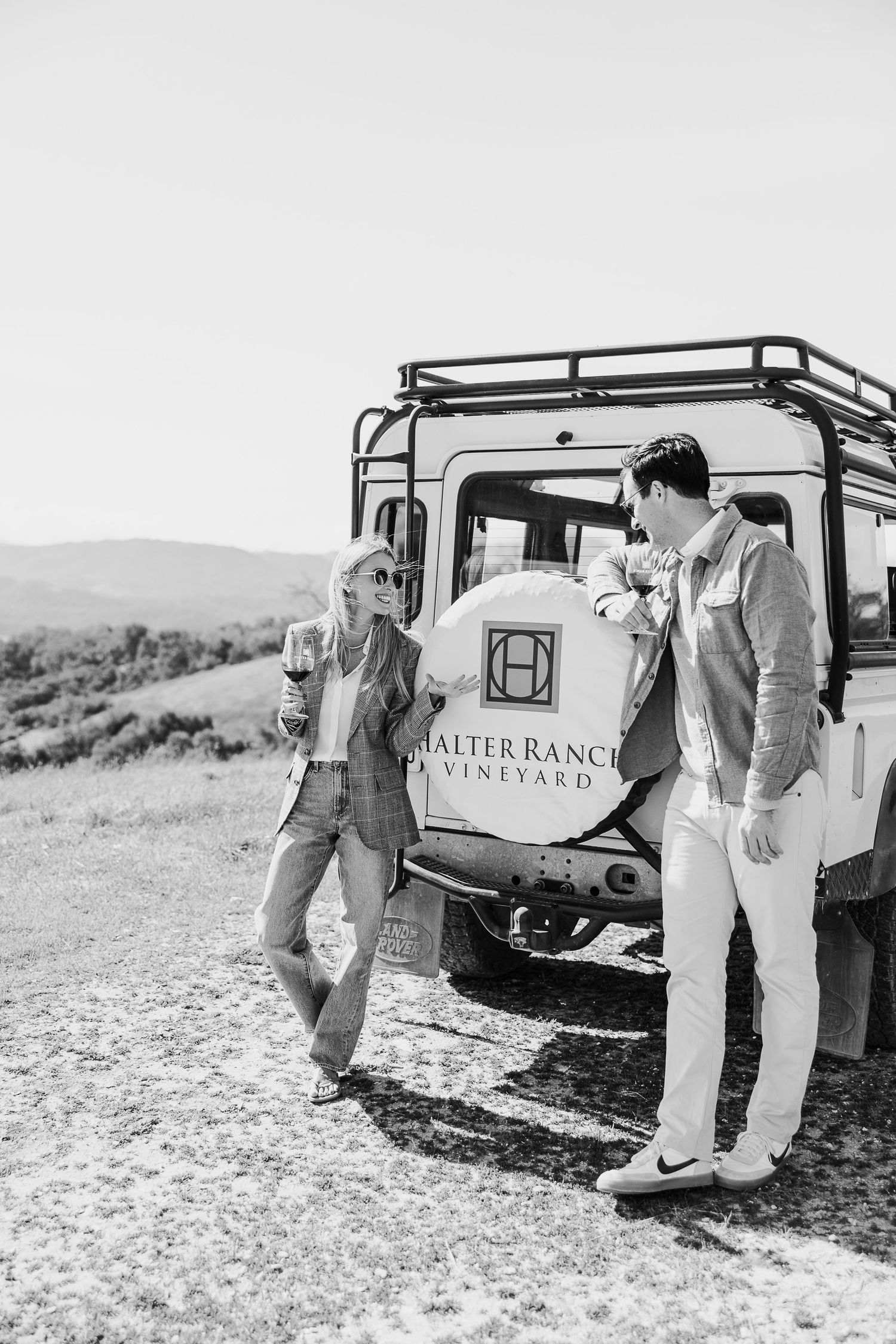 Vintage-style black and white photos of a couple by a vineyard tour vehicle.