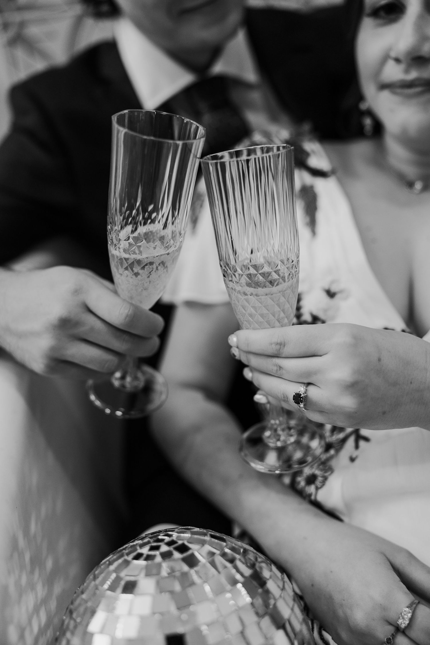 Close-up of crystal champagne flutes with a disco ball reflection.