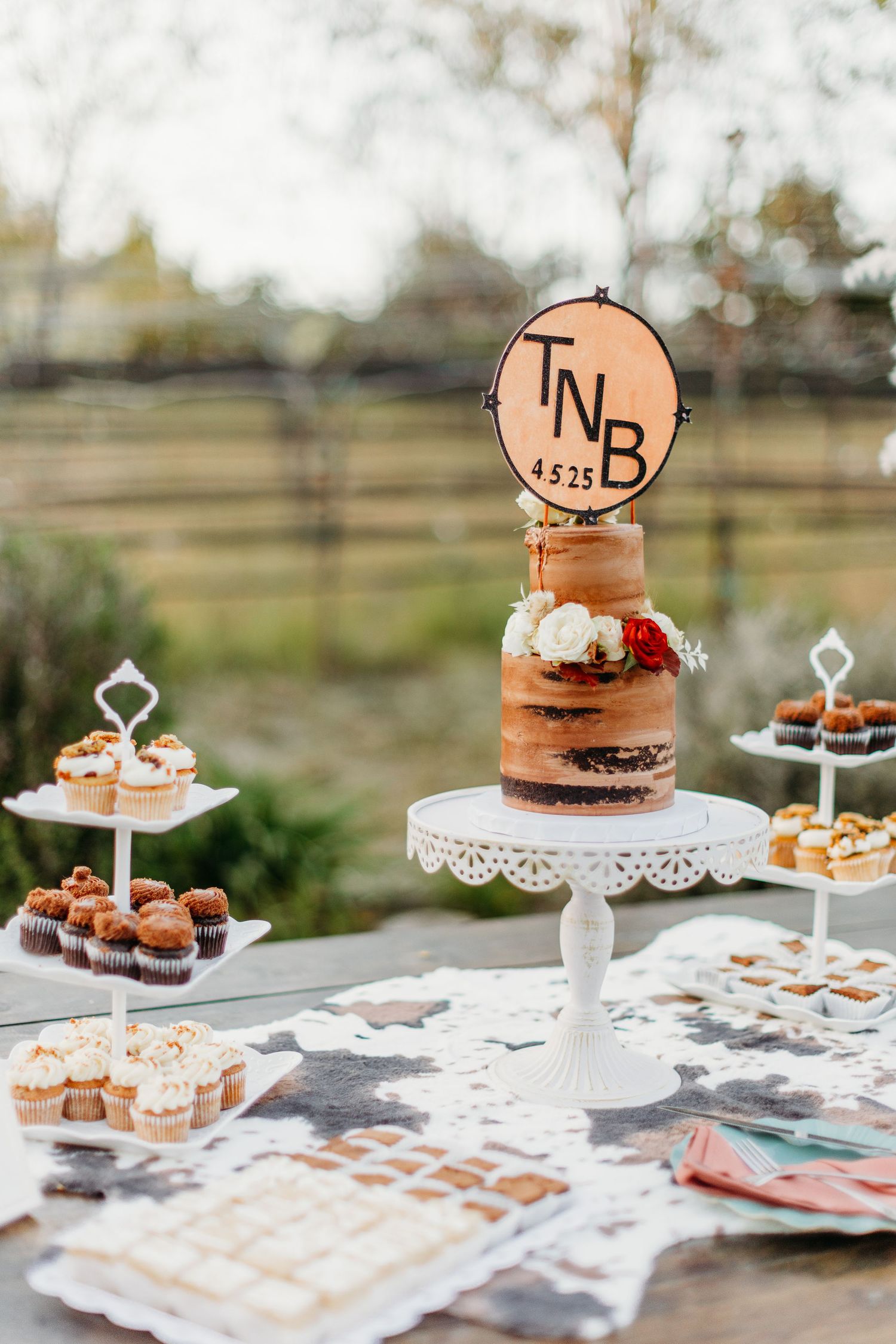 Wedding dessert display with monogrammed cake topper and tiered serving stands.