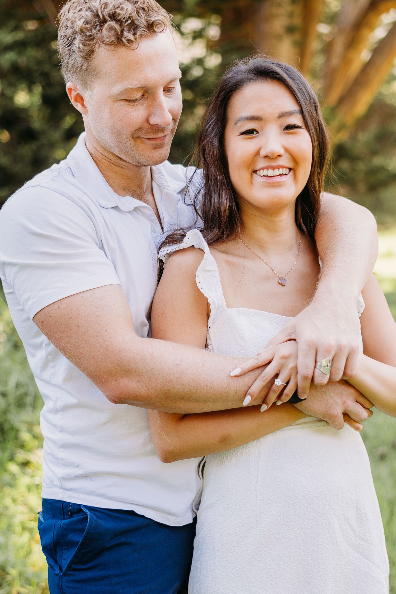A tender moment between a couple in casual attire embracing outdoors with golden sunlight.