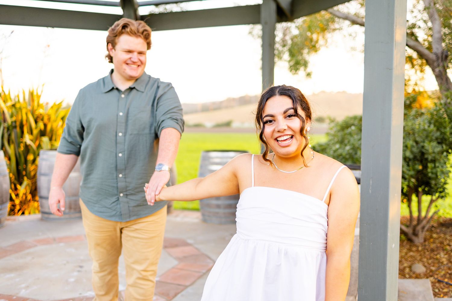 Couple holding hands and enjoying moment together under gazebo during sunset.
