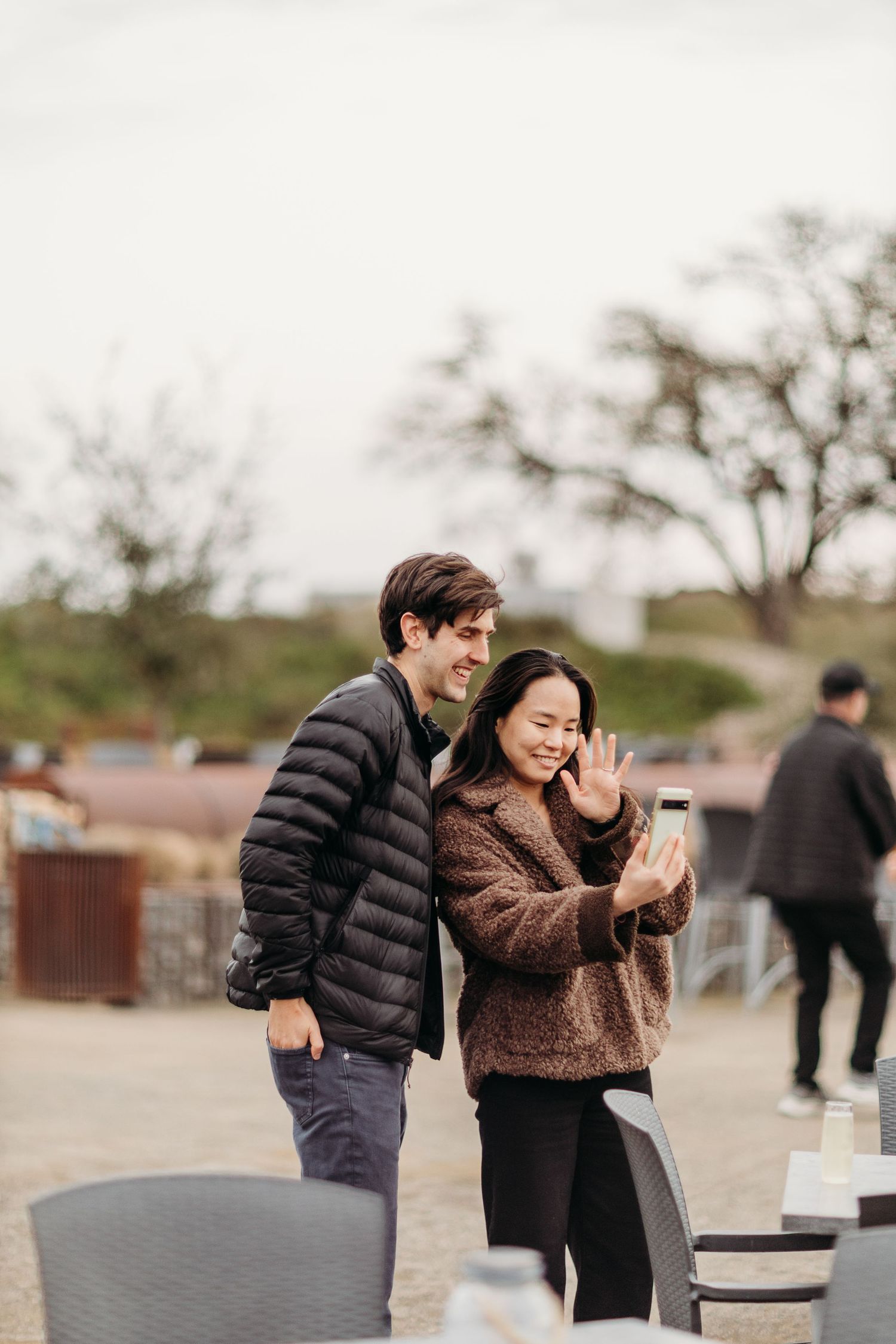 Two people sharing a joyful moment outdoors near benches and trees.