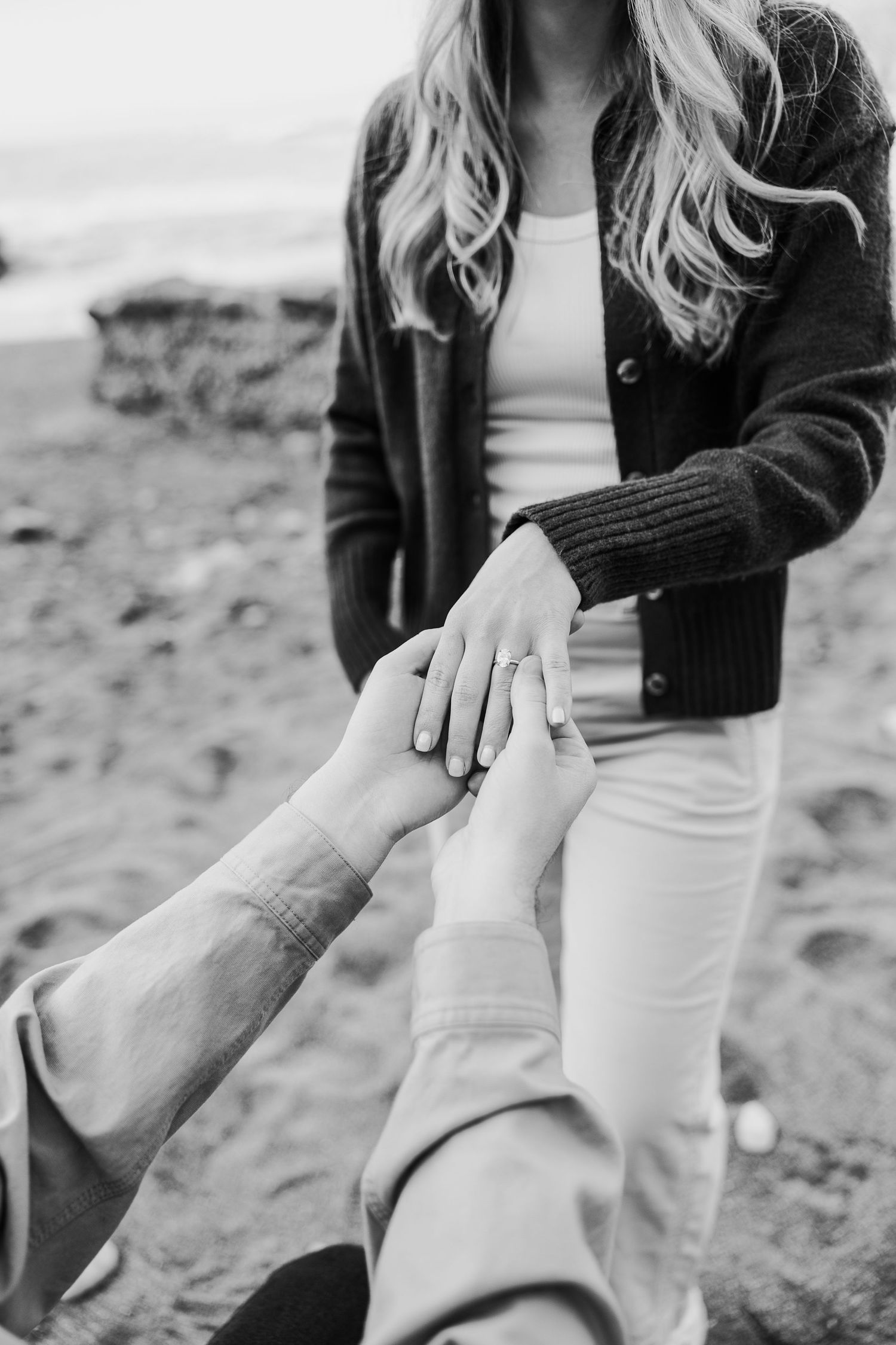Black and white photo series showing someone removing shoes and socks while sitting on sandy beach.
