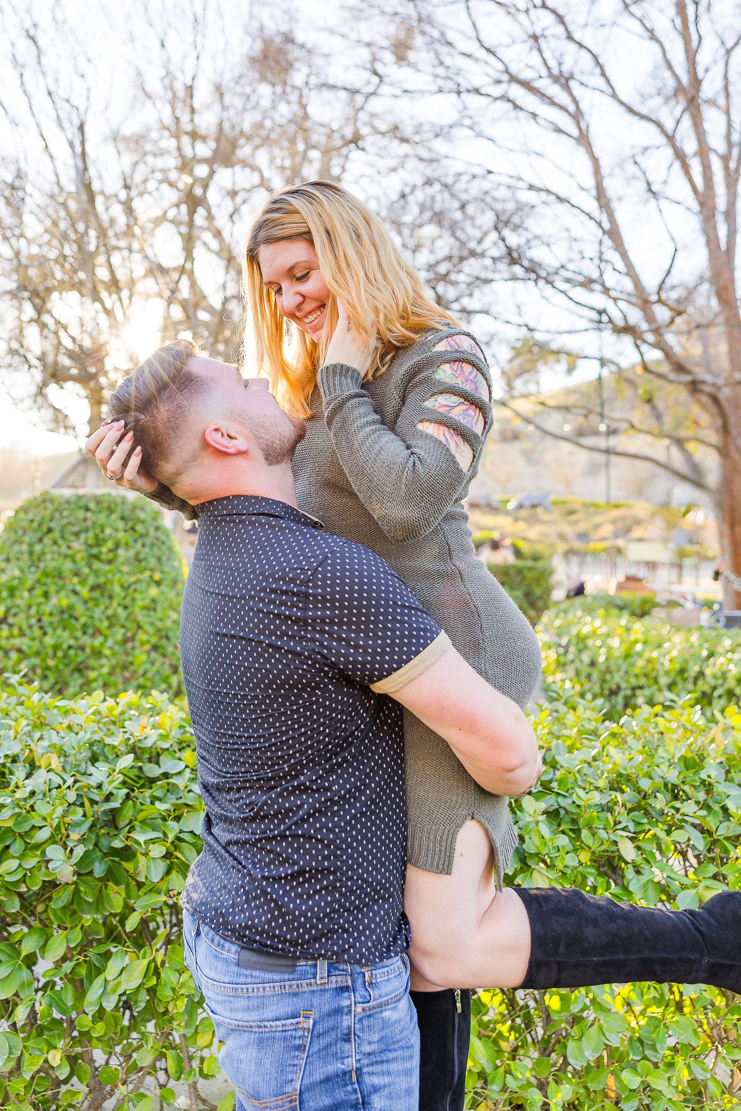 A romantic moment captured as a couple shares a playful lift in a garden setting.