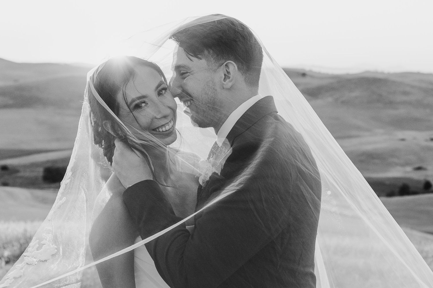 A couple embraces during golden hour in a scenic outdoor wedding photoshoot.